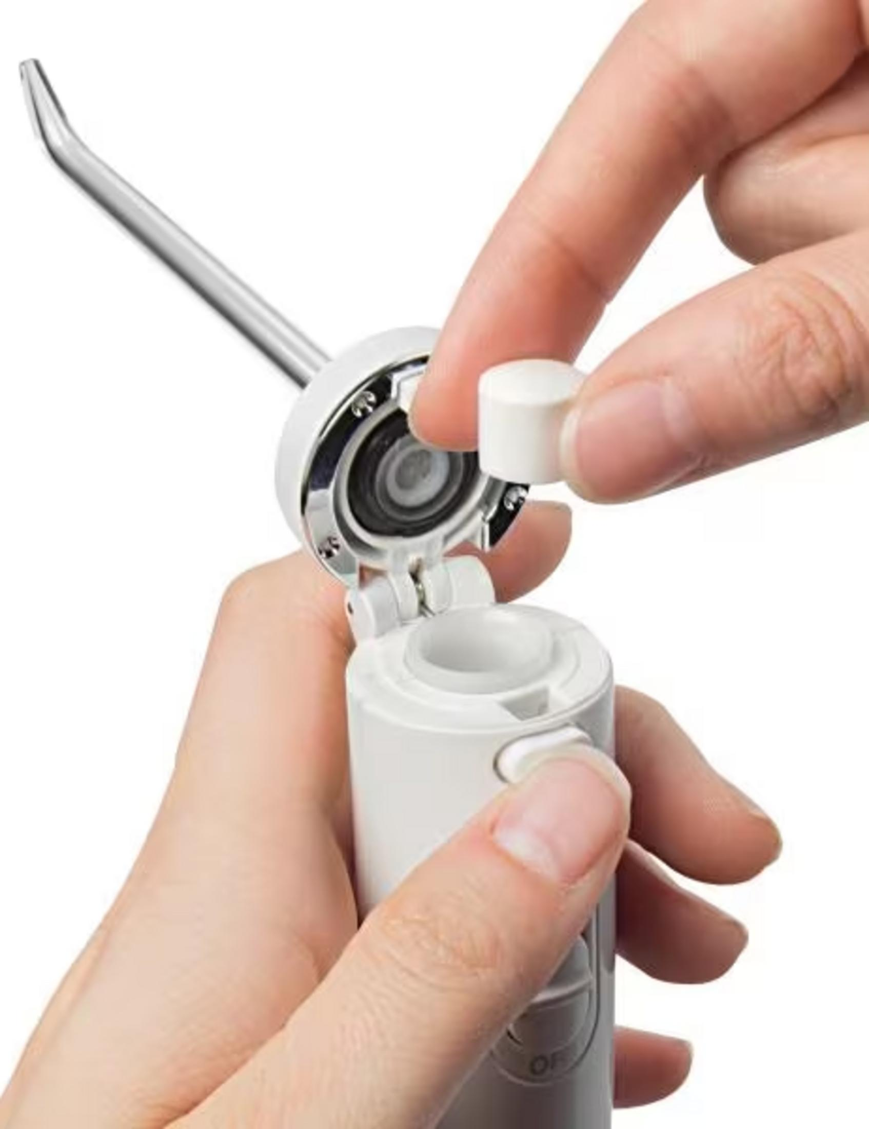 Una mano inserisce un tappo bianco in un idropulsore aperto.