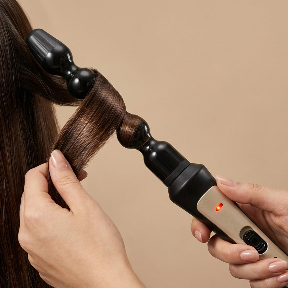 Una mano riza cabello castaño con un rizador dorado y negro con luz roja.