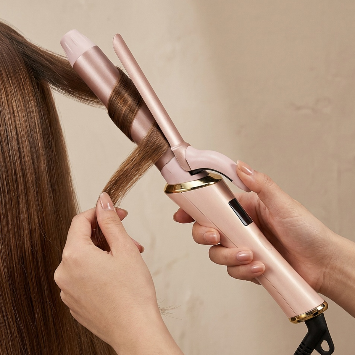 Eine Person kräuselt braunes Haar mit einem rosafarbenen Lockenstab.