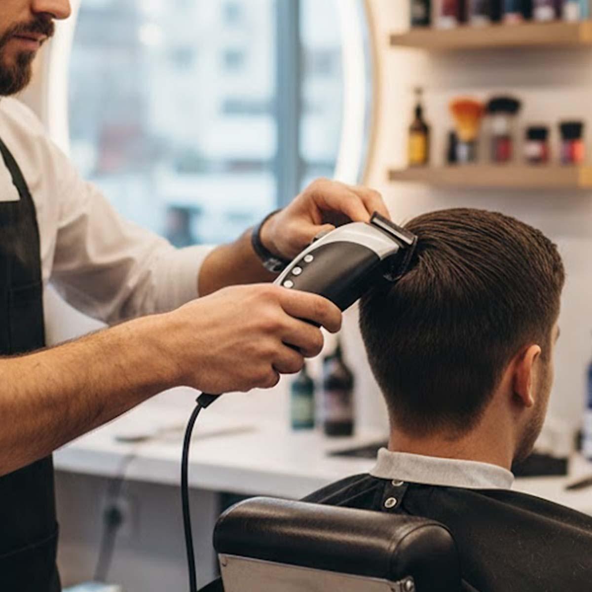 Un coiffeur coupe les cheveux d'un homme avec une tondeuse.
