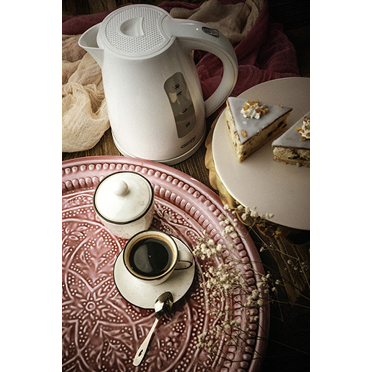 Biały czajnik stoi obok kawałków ciasta i kawy na tacy.