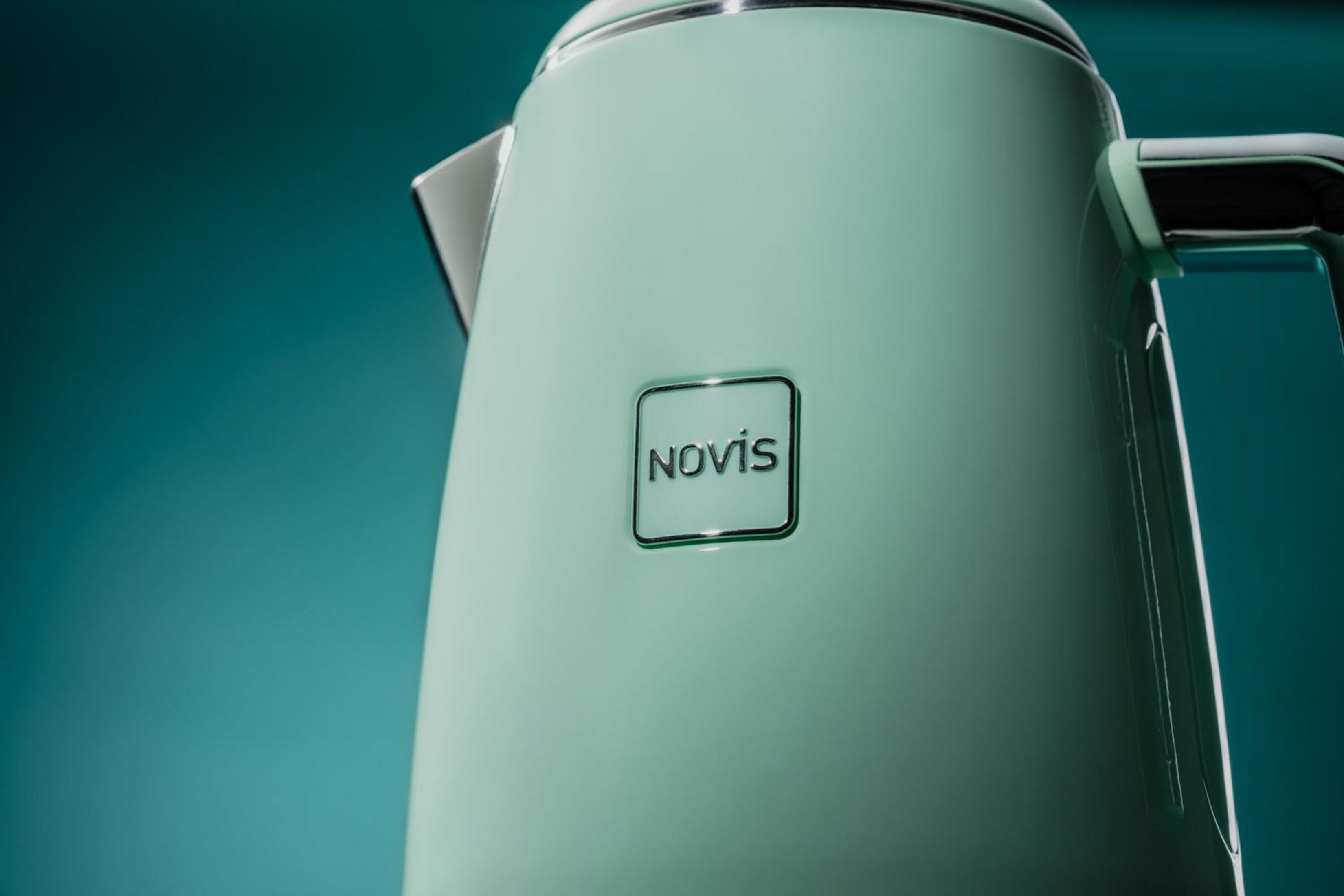 Ein türkisfarbener Wasserkocher mit dem Novis-Logo steht vor einem türkisfarbenen Hintergrund.