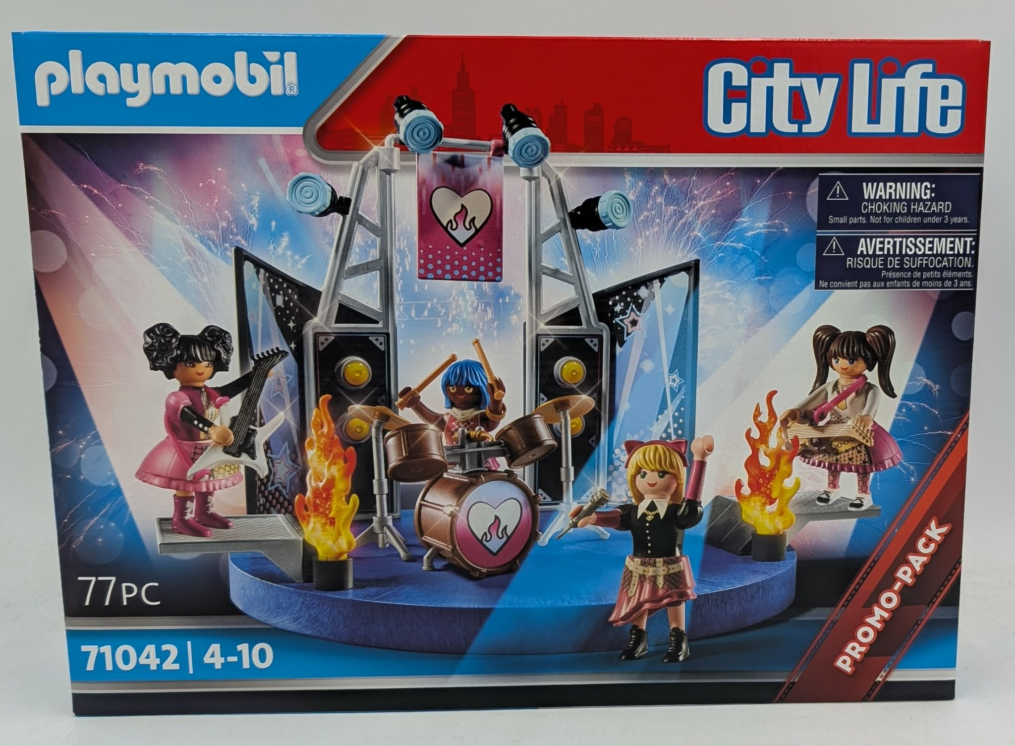 Playmobil-Set mit vier Figuren auf einer Bühne mit Schlagzeug und Gitarren vor Feuerwerk.