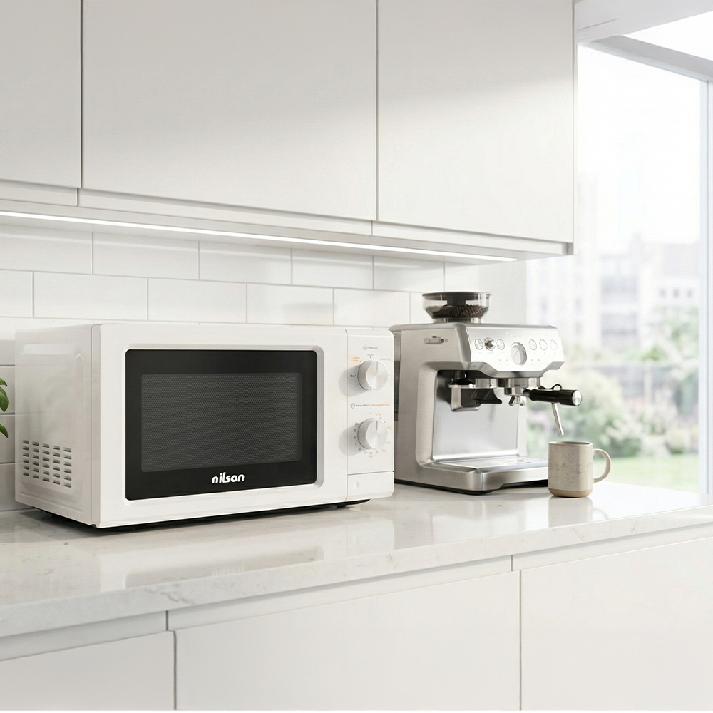Un microondas blanco y una cafetera plateada en un mostrador de cocina.