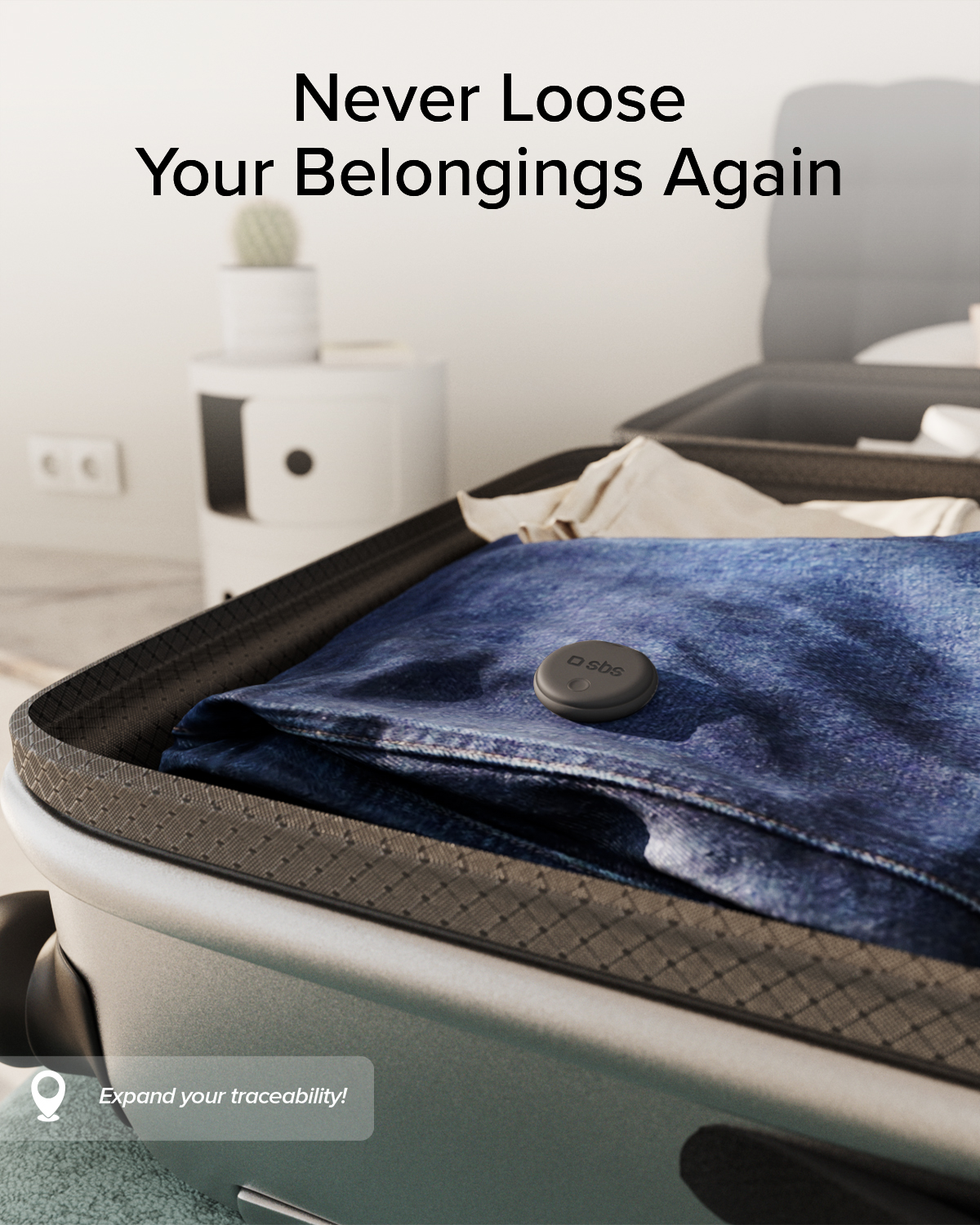 Un tracker grigio poggia su jeans blu dentro una valigia aperta.