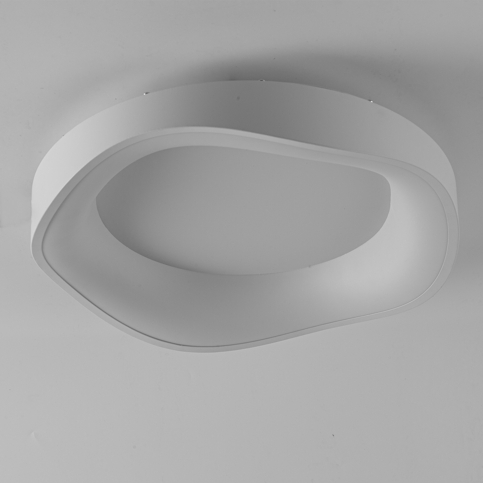 Una lámpara de techo blanca con diseño curvo, montada en un techo.