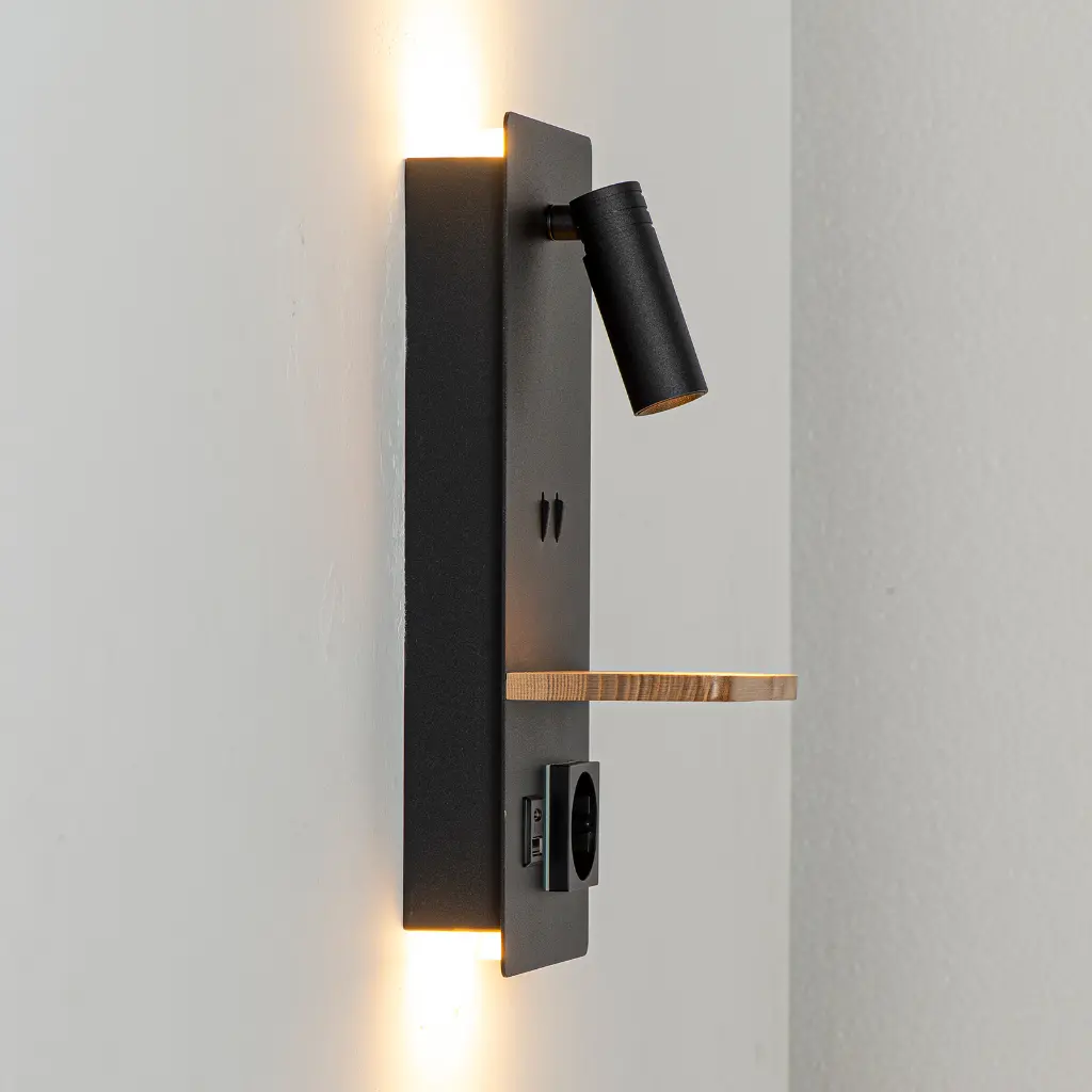Foco de pared negro con estante de madera y enchufe. Luz cálida ilumina arriba y abajo.
