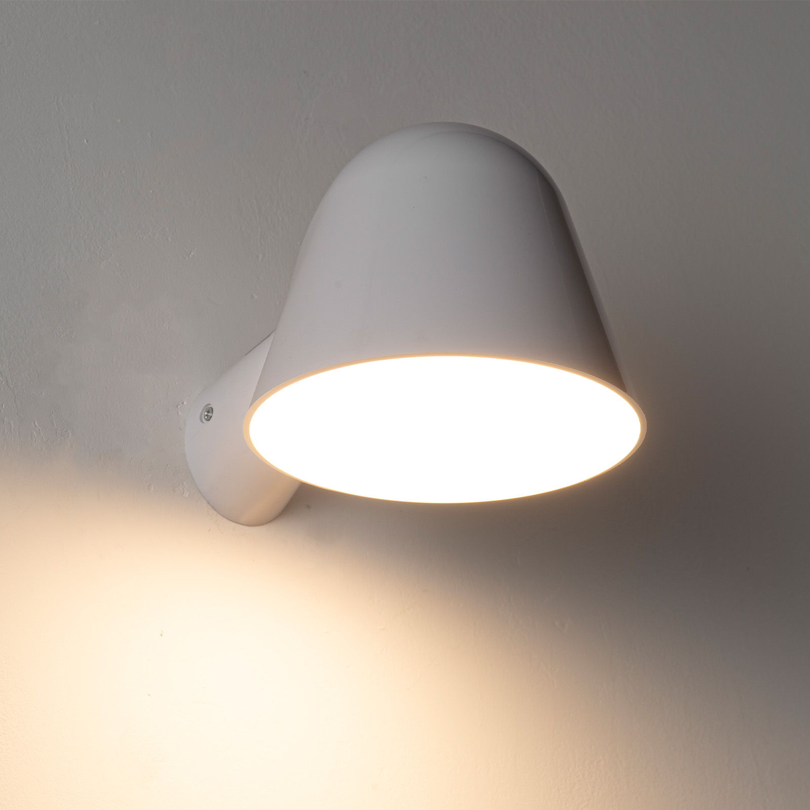 Una lámpara de pared blanca brilla intensamente contra una pared texturizada.