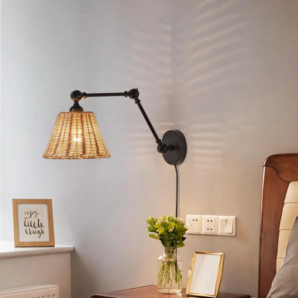 Una lámpara de pared ajustable con pantalla de ratán ilumina una pared junto a una cama.