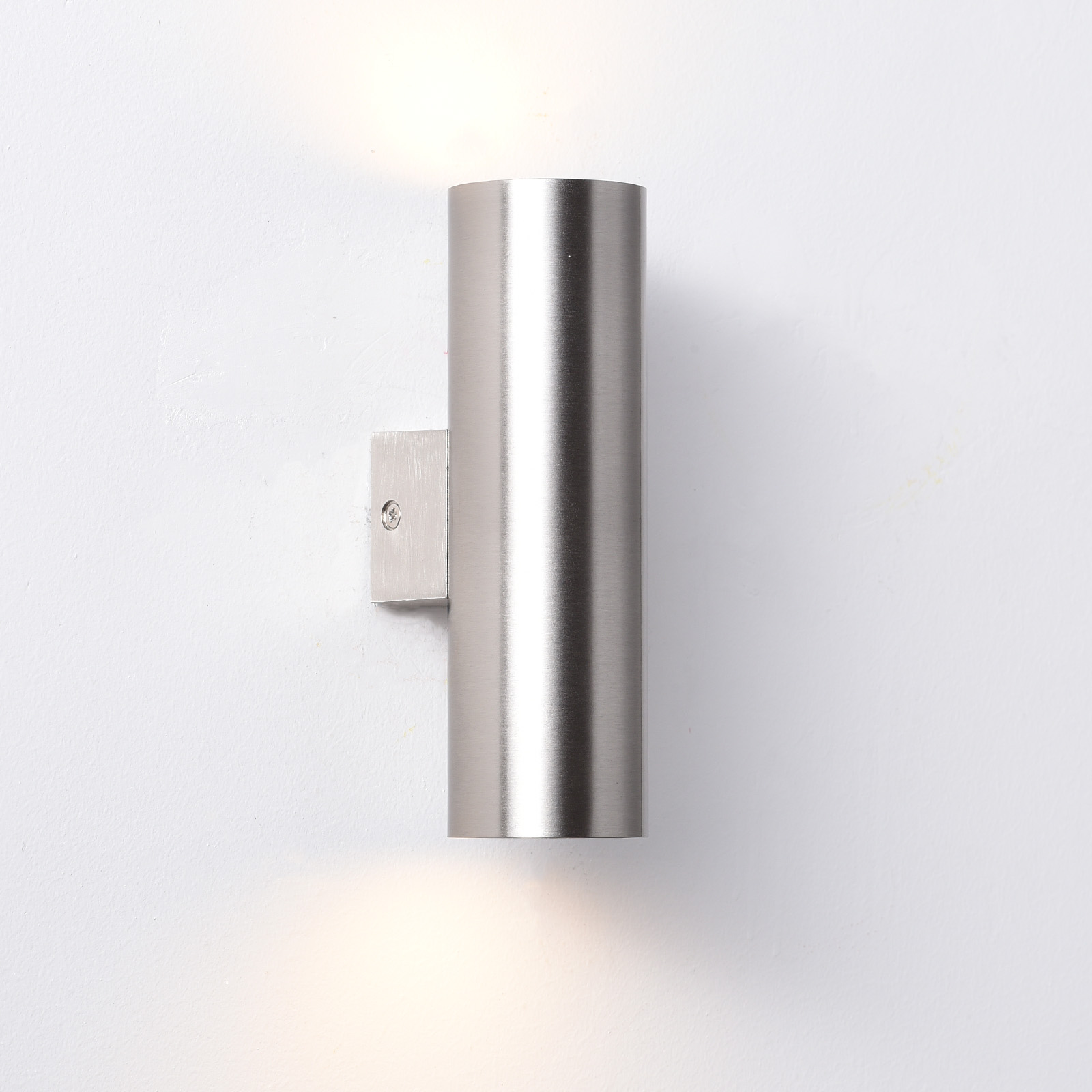 Lámpara de pared cilíndrica de metal con haces de luz hacia arriba y abajo.