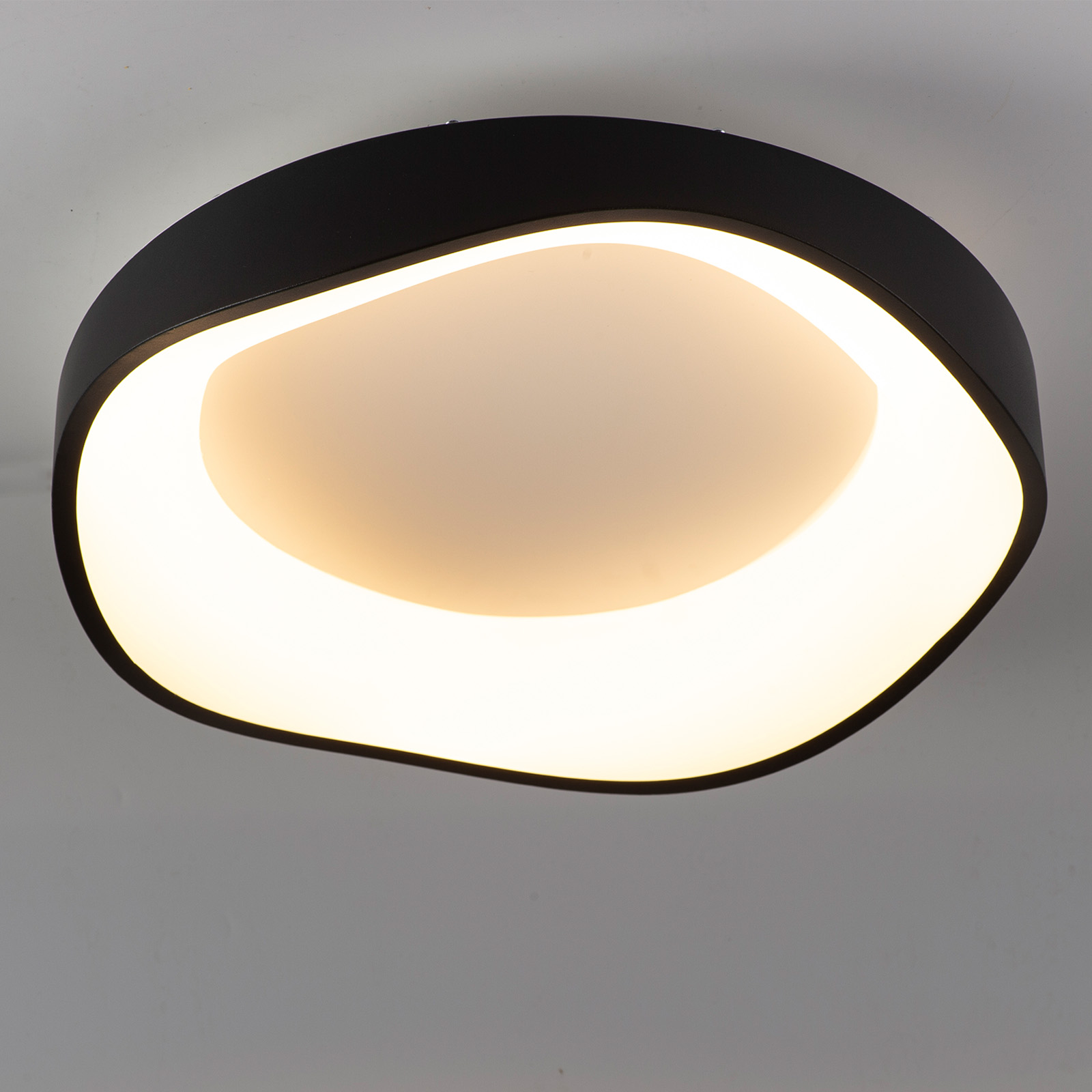 Moderna lámpara de techo negra con iluminación indirecta cálida.