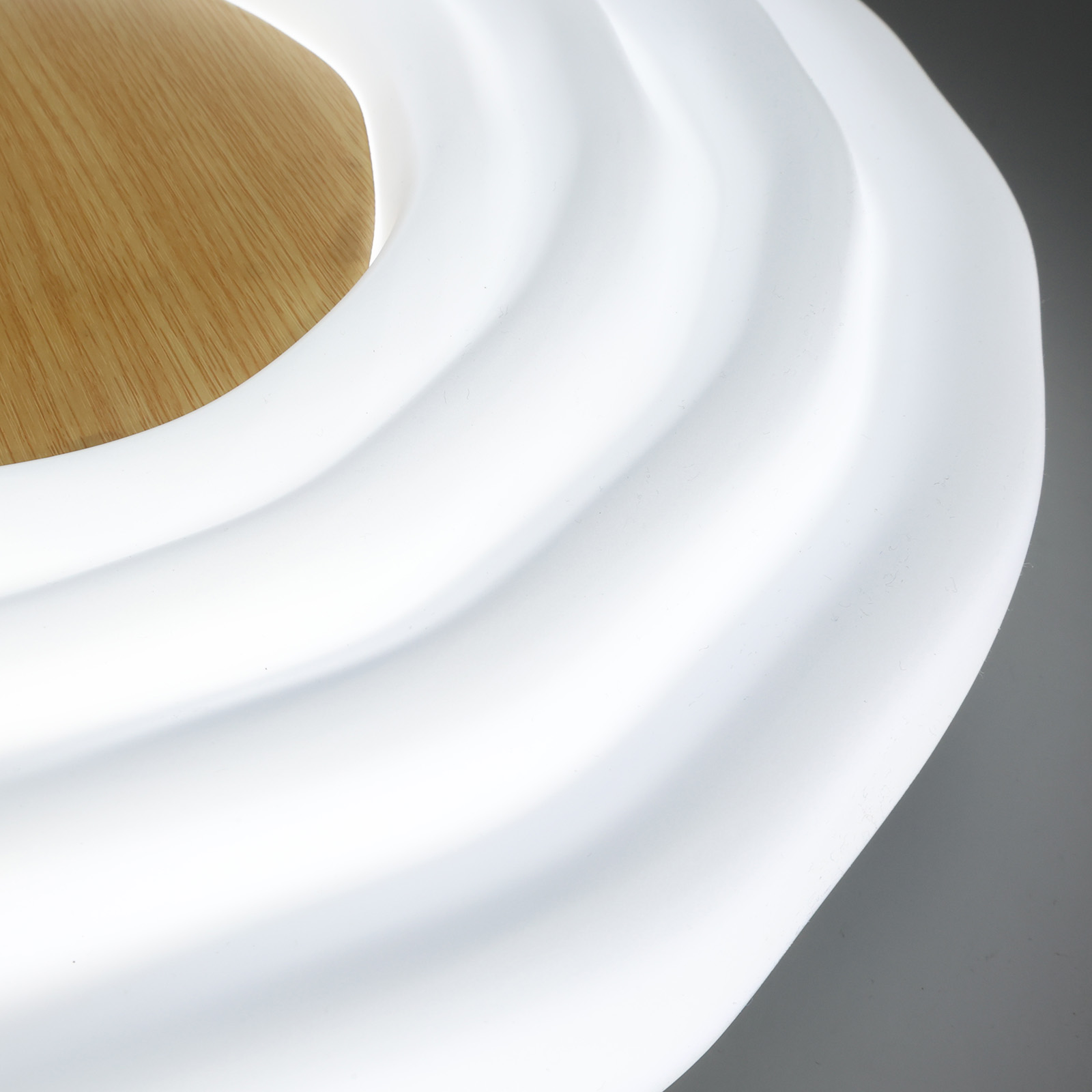 Primer plano de una lámpara translúcida blanca de forma orgánica con detalles de madera.