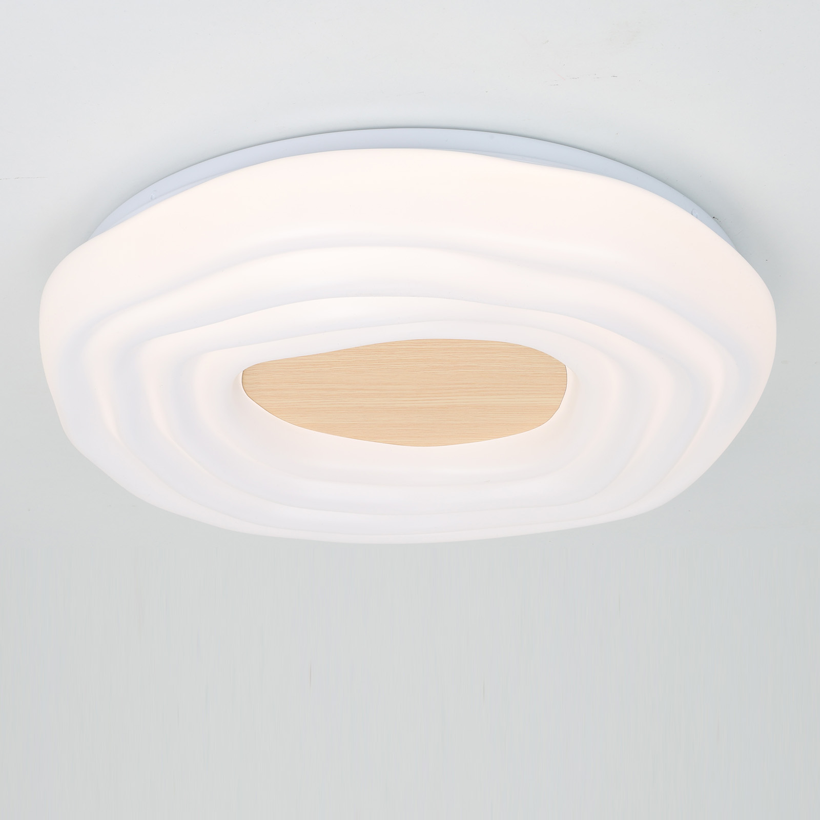 Una lámpara de techo blanca con centro de madera y forma ondulada.
