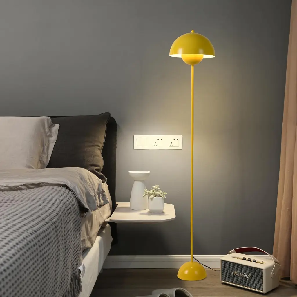 Una lámpara de pie amarilla con forma de hongo junto a una cama y mesita de noche.