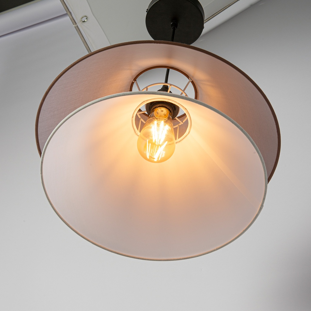 Una bombilla Edison vintage cuelga en una pantalla de lámpara de doble capa, proyectando un brillo cálido.
