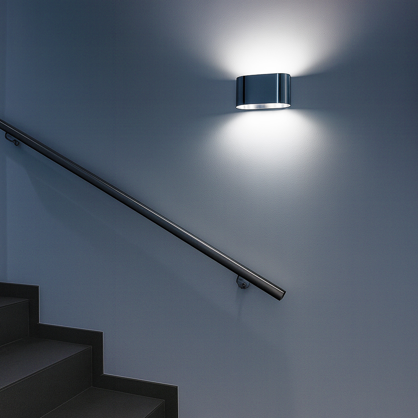 Una lámpara de pared ilumina una pared gris junto a una escalera con pasamanos.