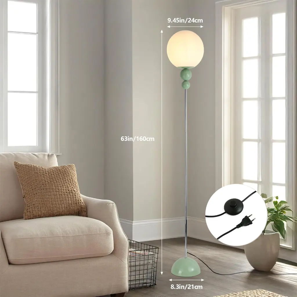 Una elegante lámpara de pie con pantalla esférica blanca y detalle verde.