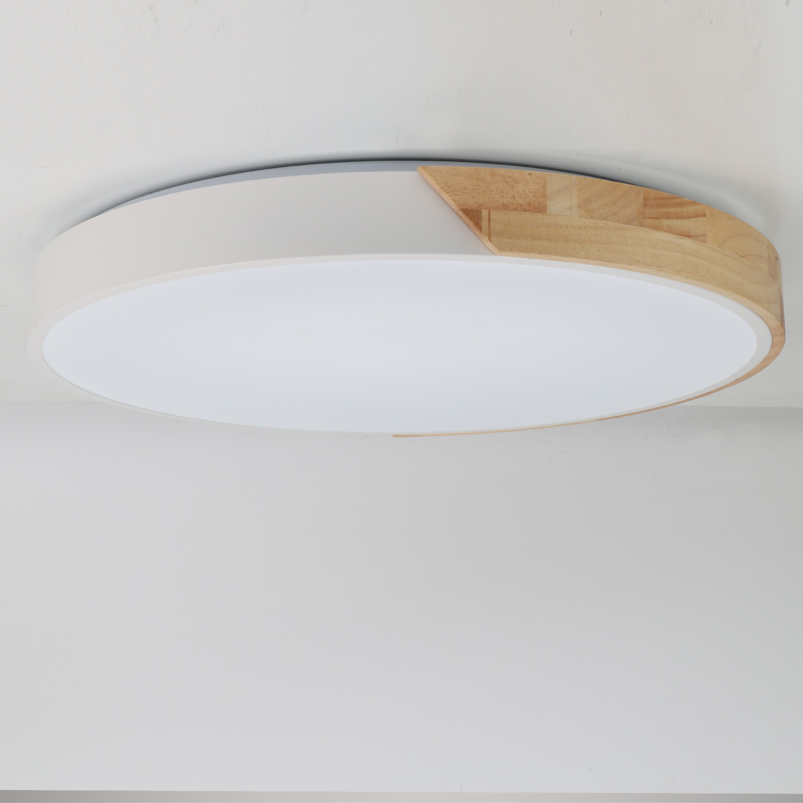 Una lámpara de techo blanca con detalles de madera, montada en un techo blanco.