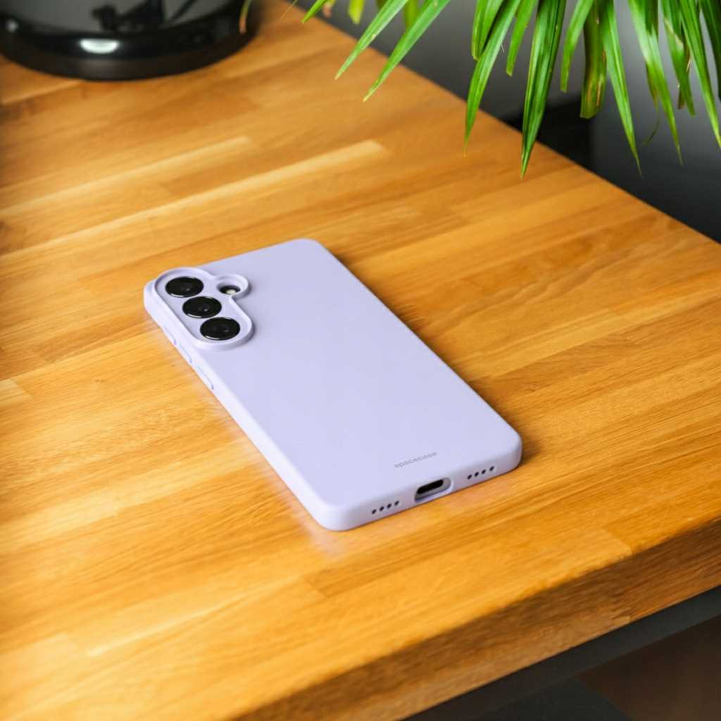 Jasnofioletowe etui na telefon z trzema aparatami leży na drewnianym stole.