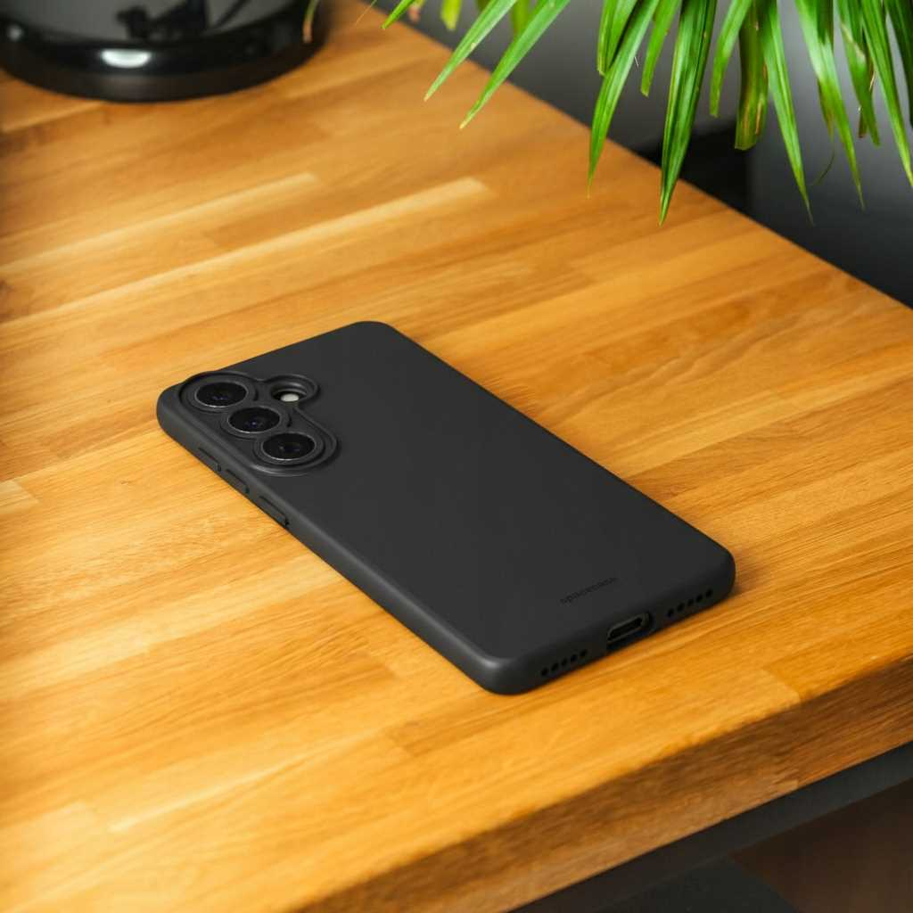 Czarny smartfon z trzema aparatami leży na drewnianym stole.