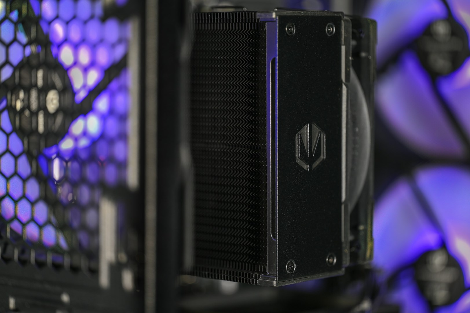 Czarny cooler CPU z wentylatorem w obudowie PC, fioletowe podświetlenie.