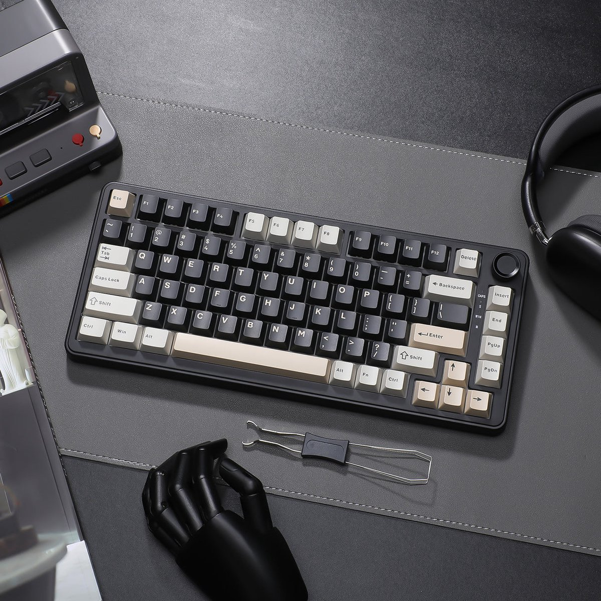 Un clavier noir avec des touches beige et blanches sur un tapis gris.