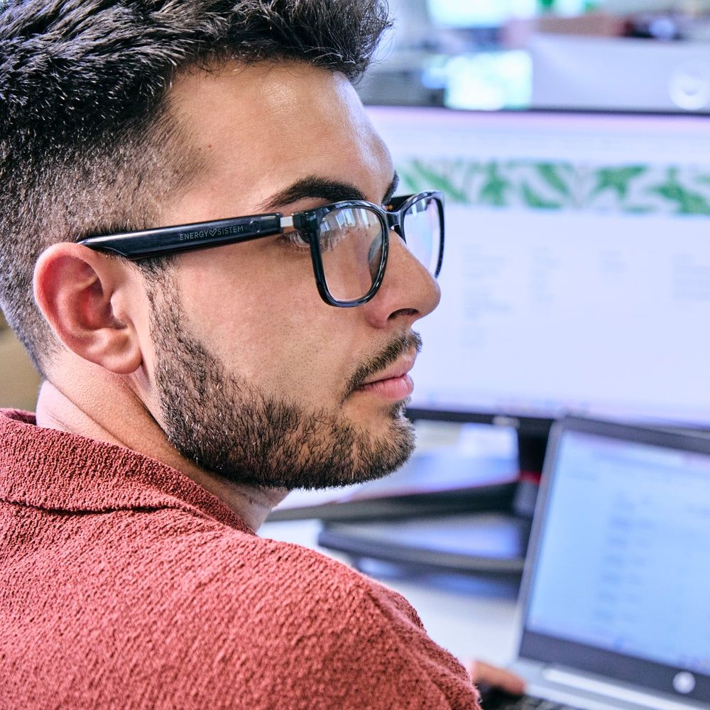 Mann mit Brille blickt auf Computerbildschirme.