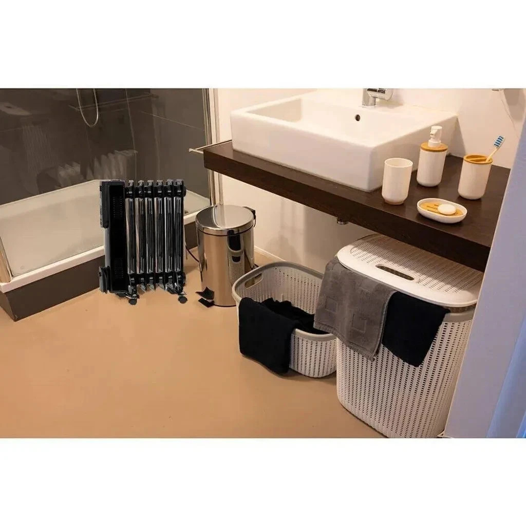 Ein schwarzer Heizkörper steht neben einer Badewanne, daneben ein Mülleimer.