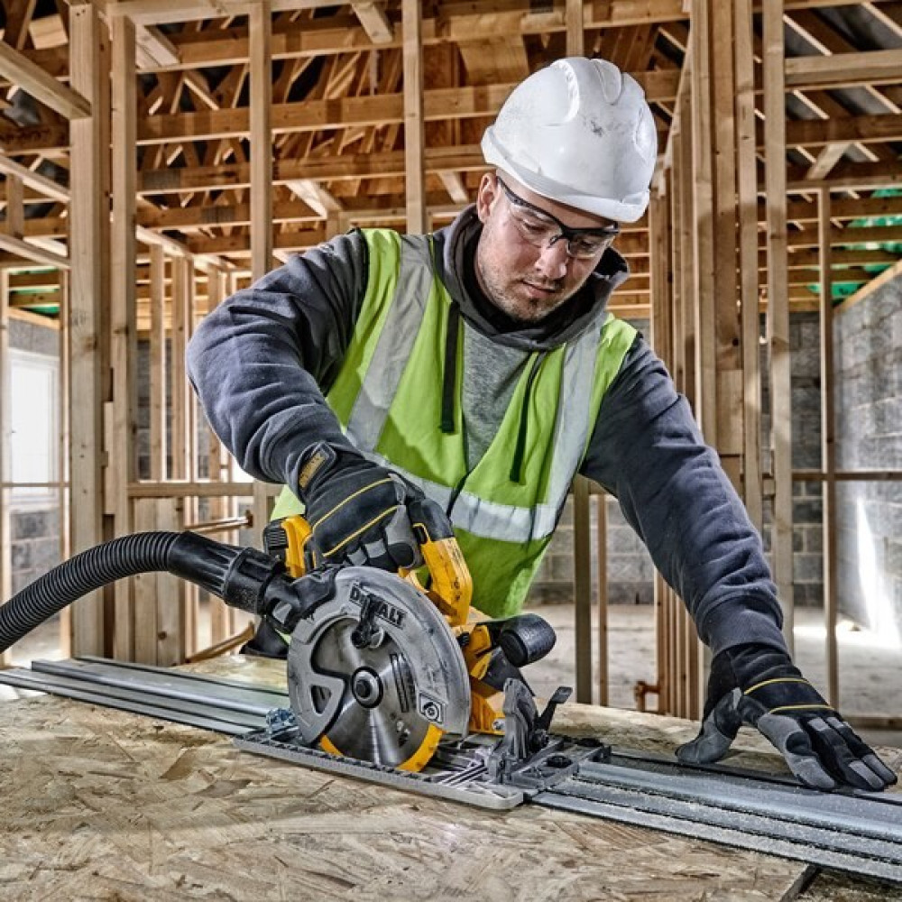 Robotnik budowlany używa piły tarczowej na placu budowy z drewnianą ramą.