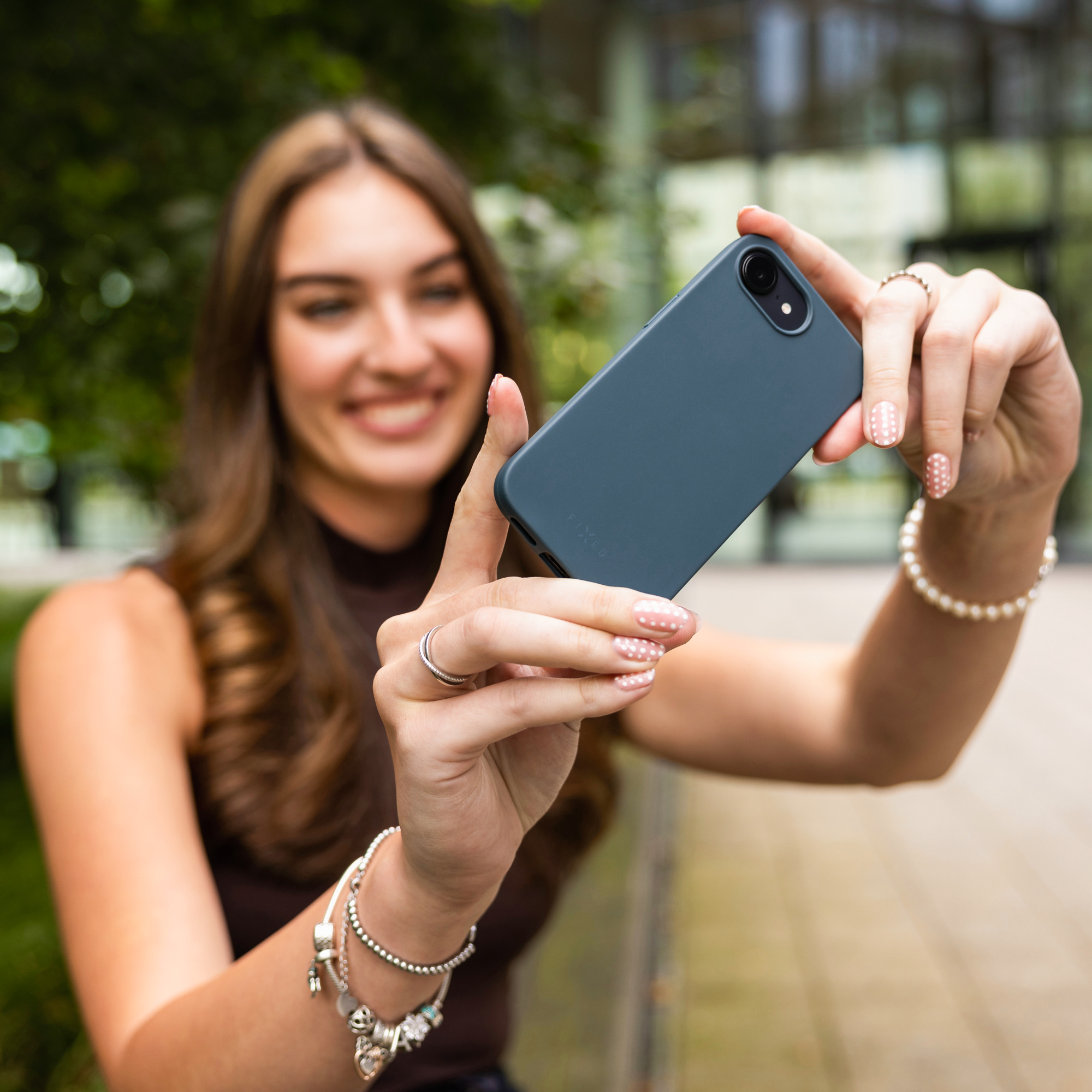 Eine lächelnde Frau macht ein Selfie mit einem blauen Handy in der Hand.