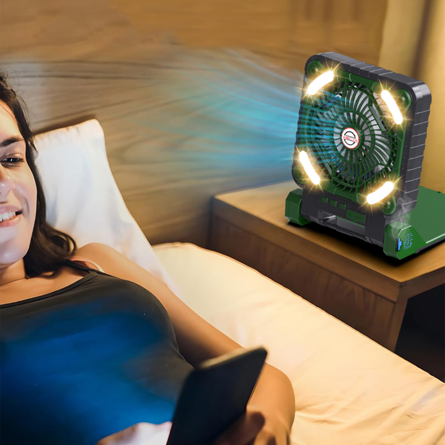 Una donna è sdraiata a letto guardando il telefono mentre una ventola illuminata soffia aria.