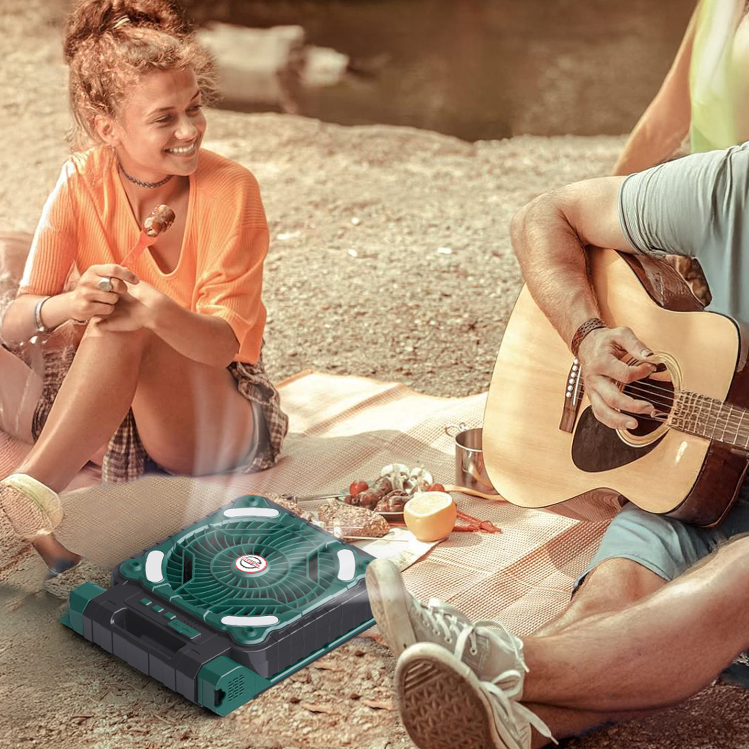 Persone che si godono un picnic con musica di chitarra e ventilatore portatile.