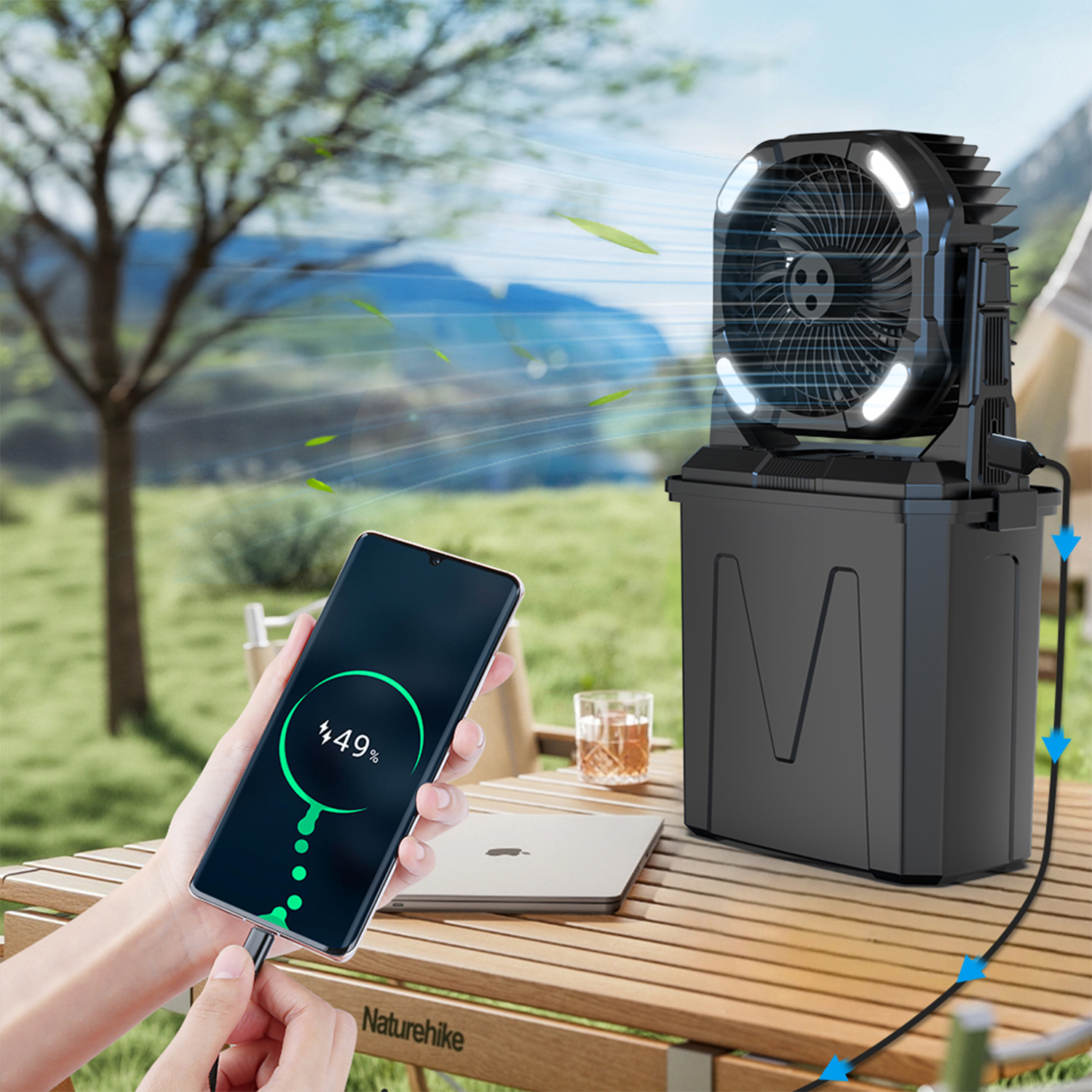 Un ventilador portátil y un smartphone cargando en una mesa de madera al aire libre.