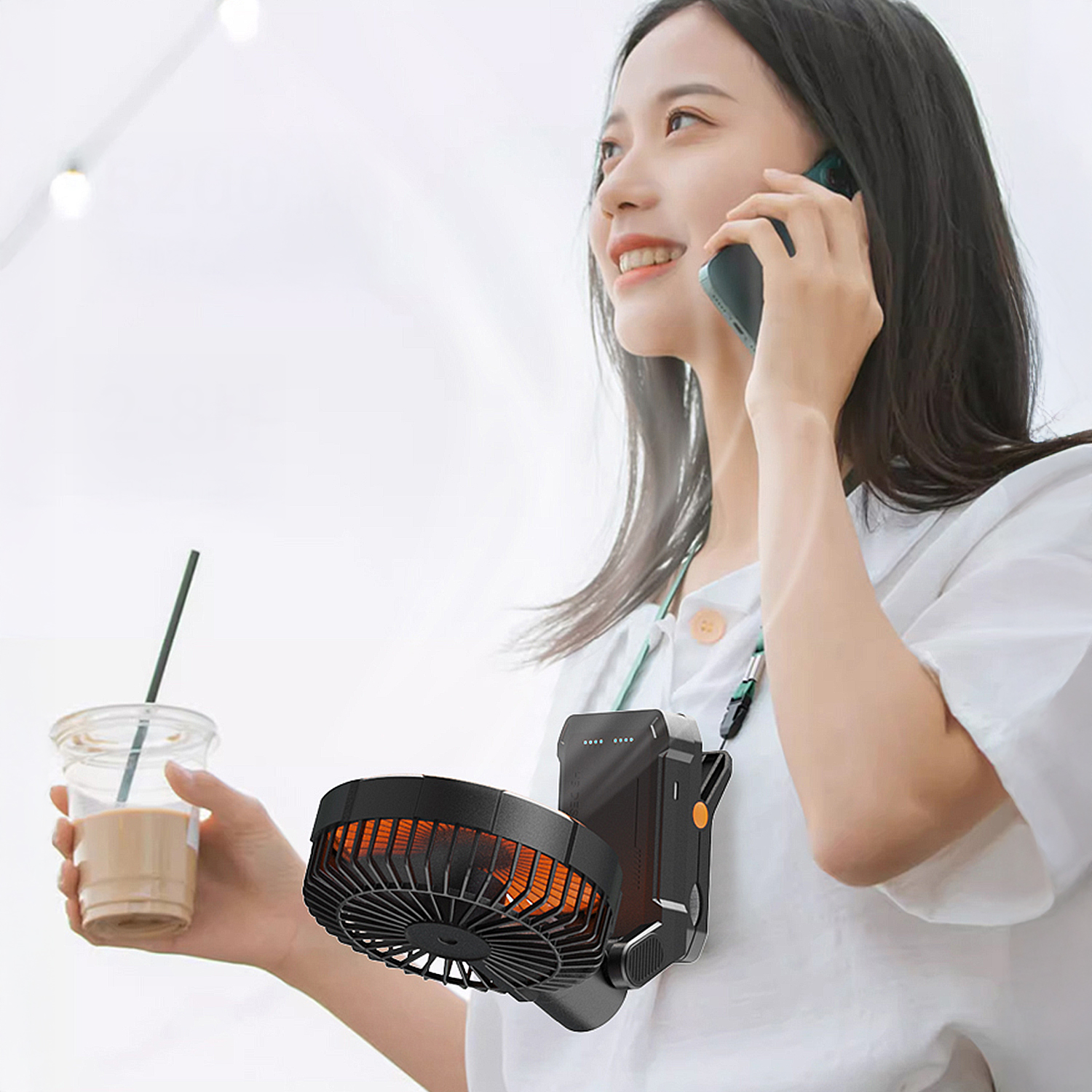 Donna con ventilatore al collo parla al telefono tenendo una bevanda.