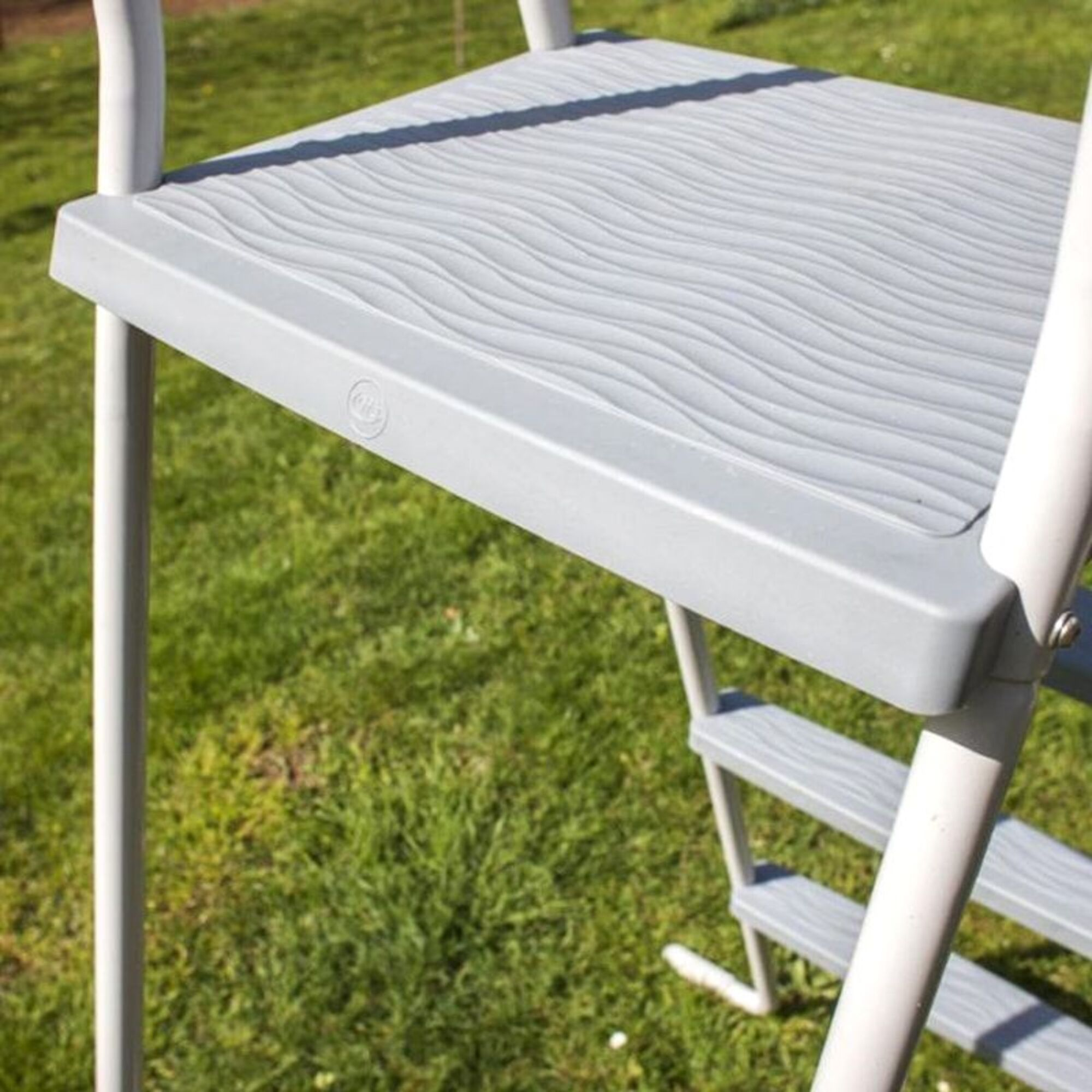 Peldaño de escalera gris con patrón de ondas sobre césped verde.