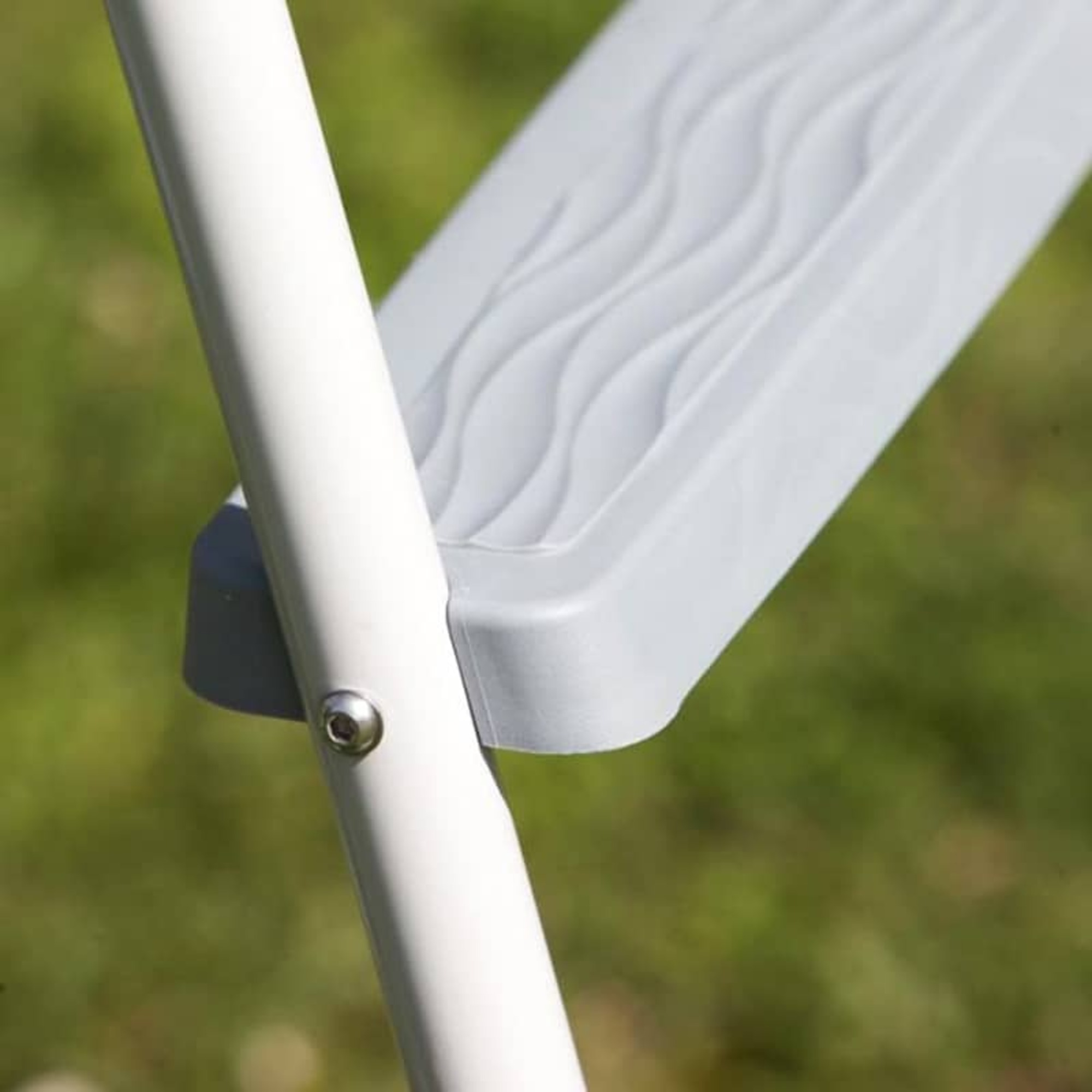 Un poste blanco y un escalón gris con patrón de ondas al aire libre.