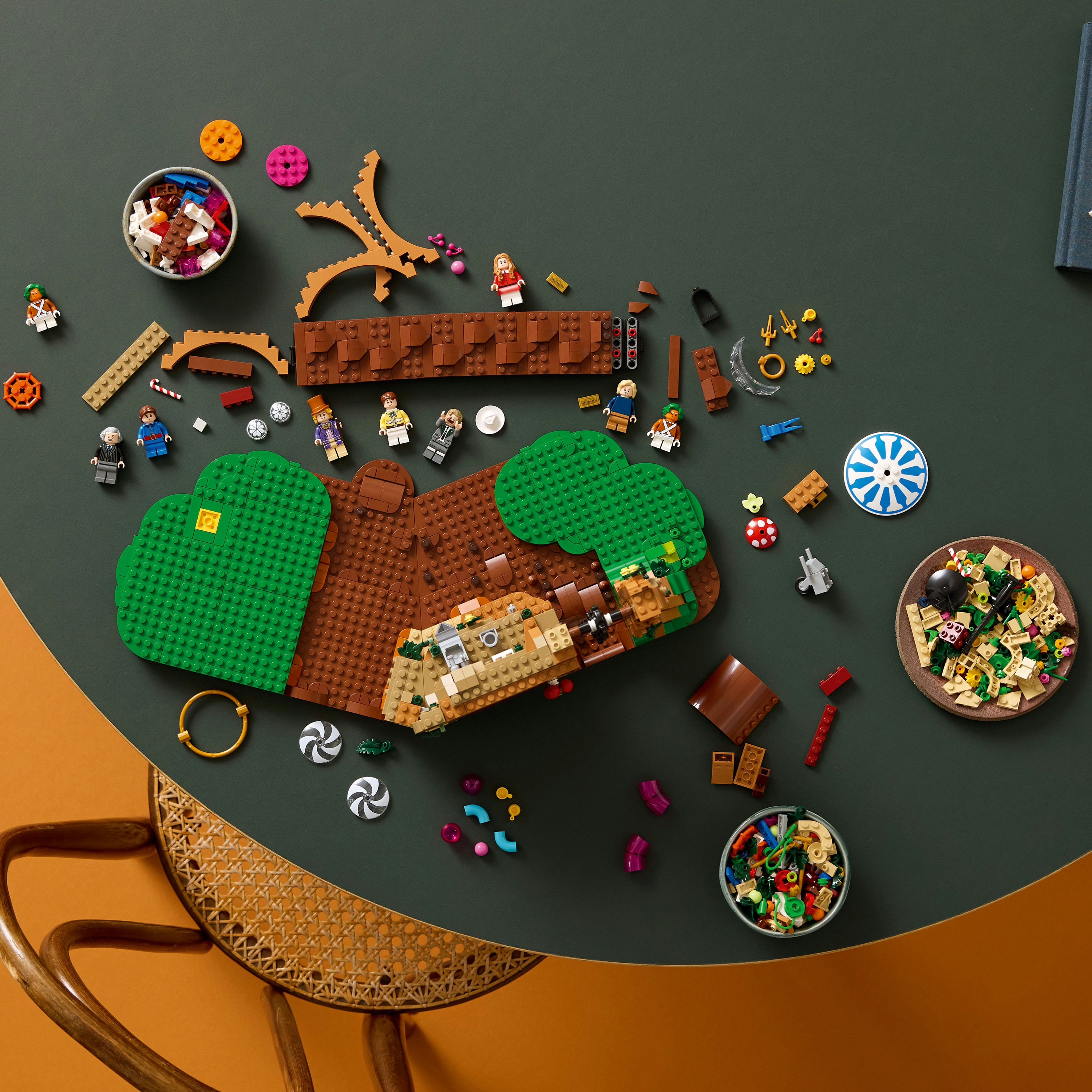 Lego stenen op groen en bruin grondplaat, met figuren en accessoires.