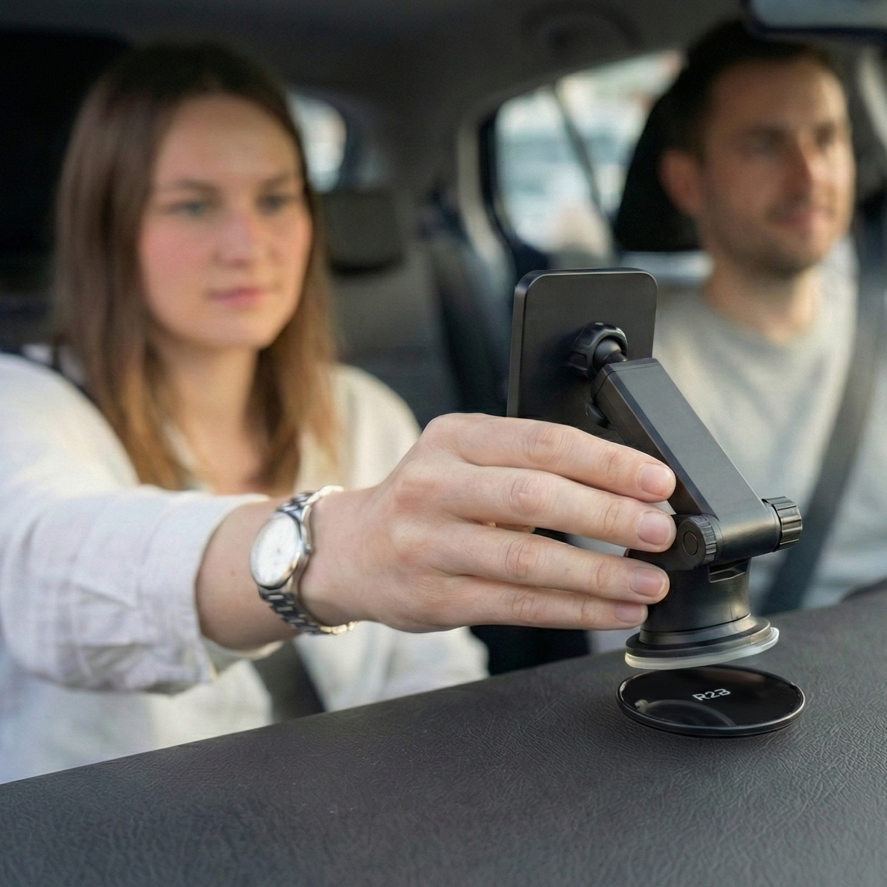 Een vrouw stelt een telefoonhouder in de auto af, met een man ernaast.