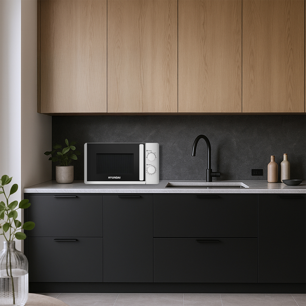 Un microondas blanco sobre una encimera de cocina con armarios negros y superiores de madera.