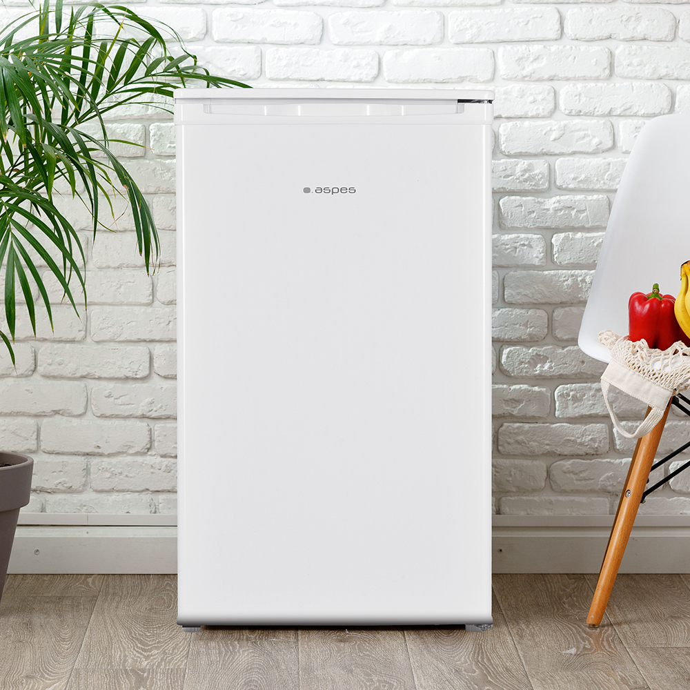 Un refrigerador blanco junto a una pared de ladrillos blancos.