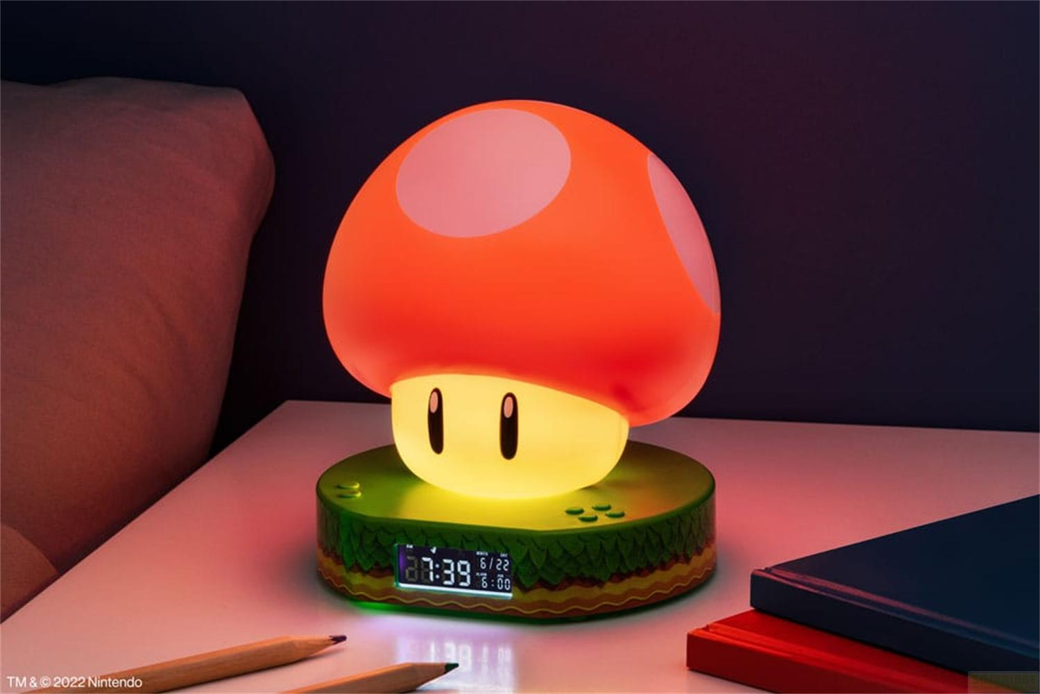 Świecąca lampa grzybek Super Mario stoi na stoliku nocnym obok łóżka.