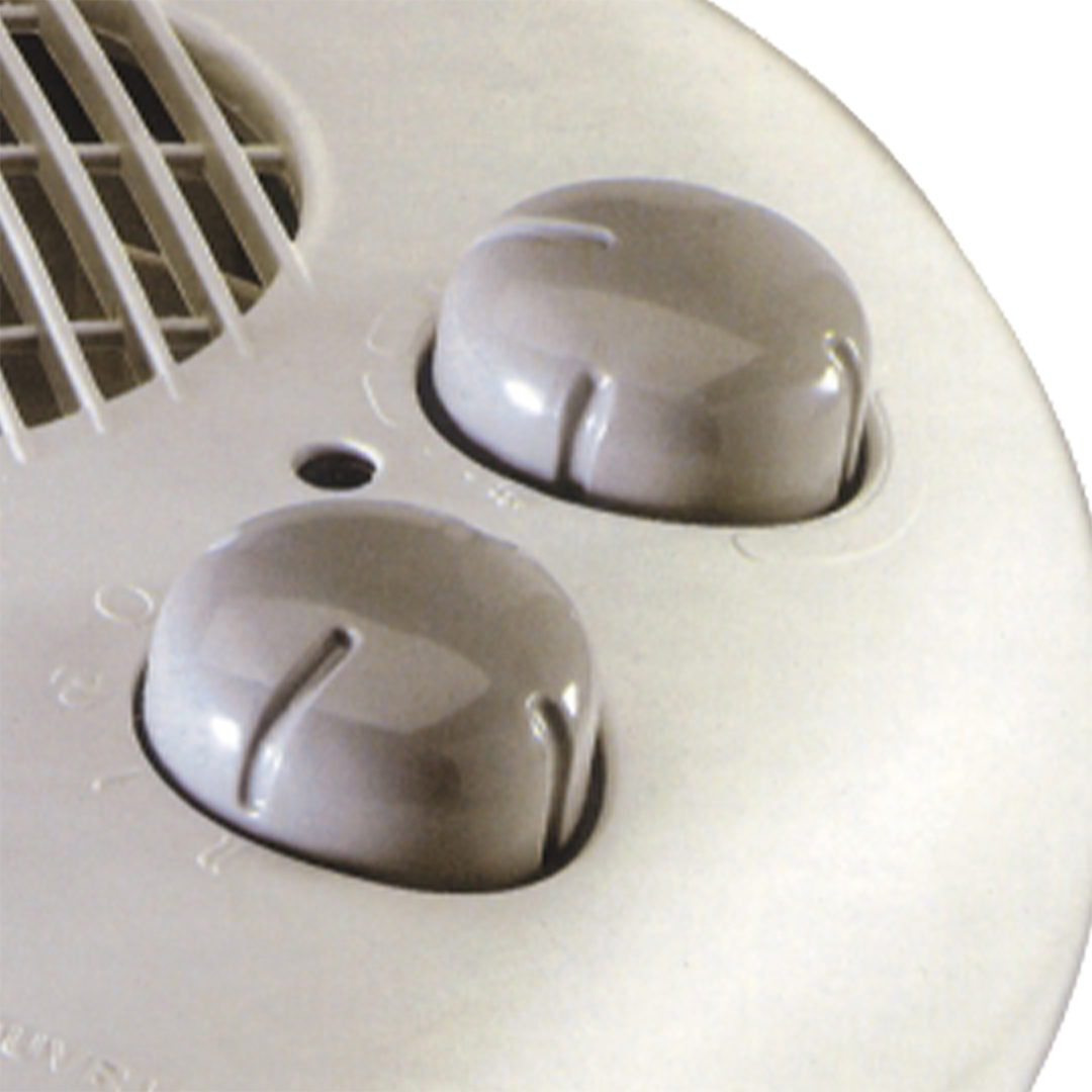 Primer plano de dos perillas giratorias grises en un electrodoméstico blanco con rejillas.