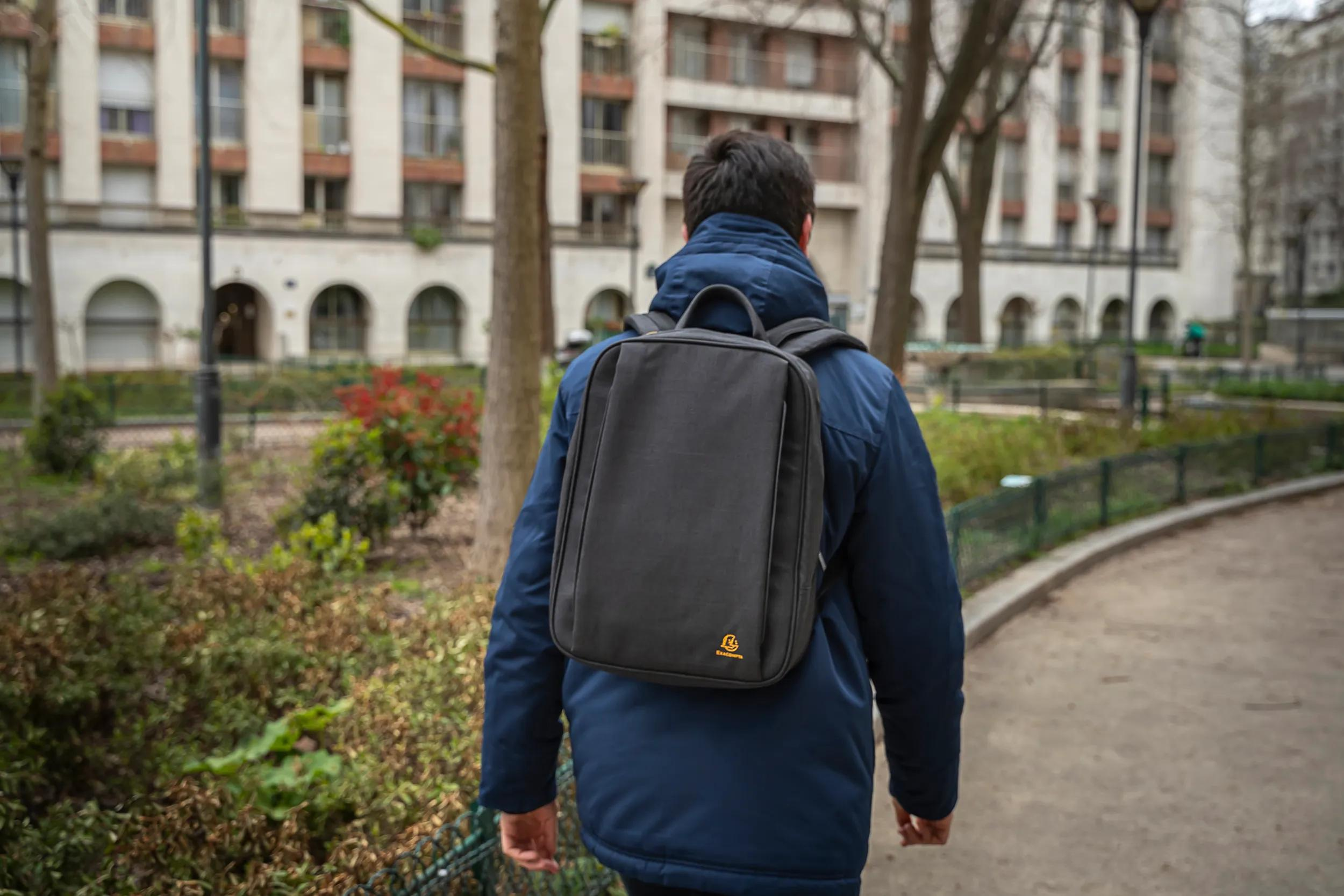 Hombre con mochila camina por un sendero frente a un edificio.