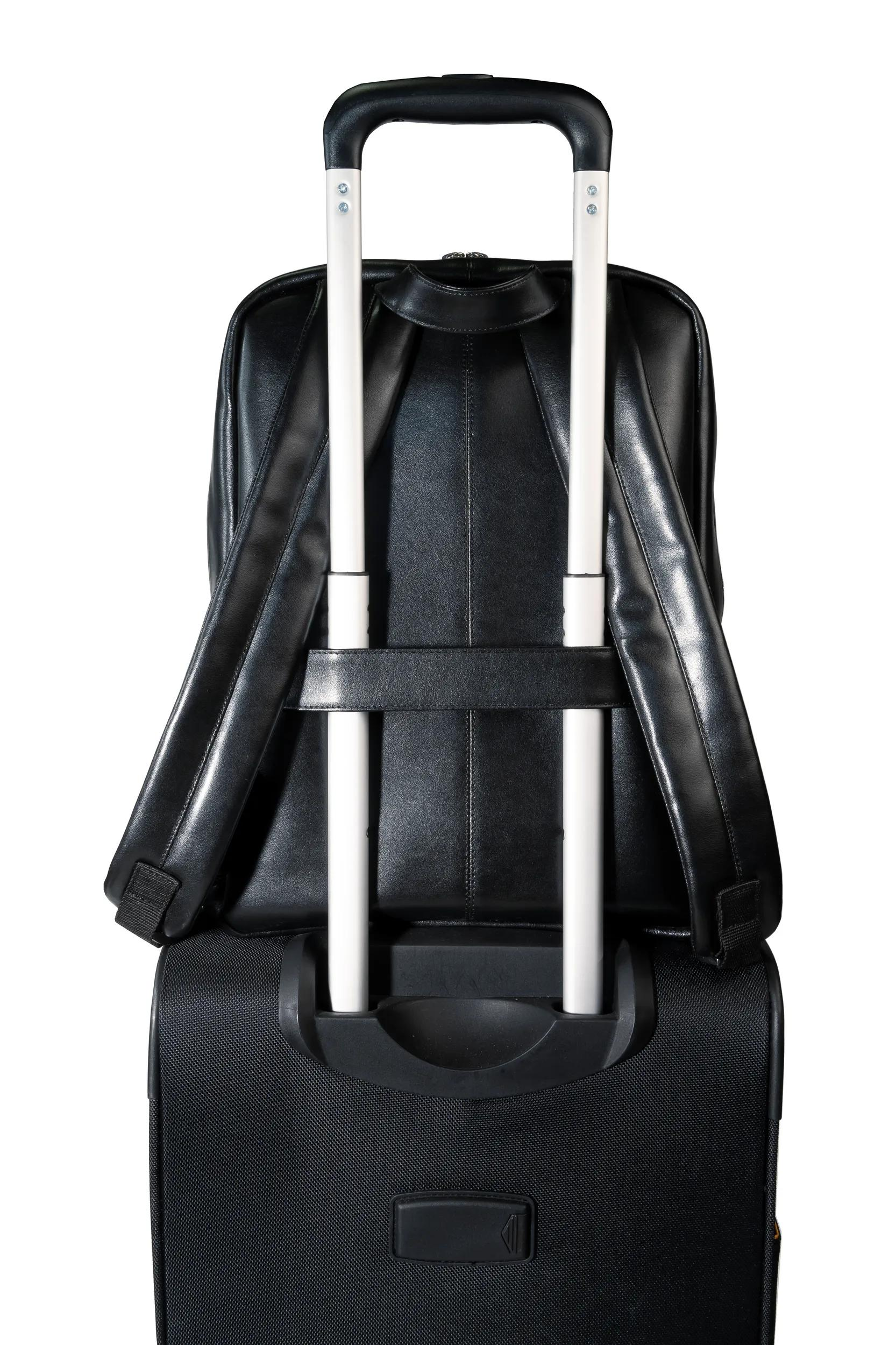Mochila negra sobre maleta de ruedas negra con asas extensibles.