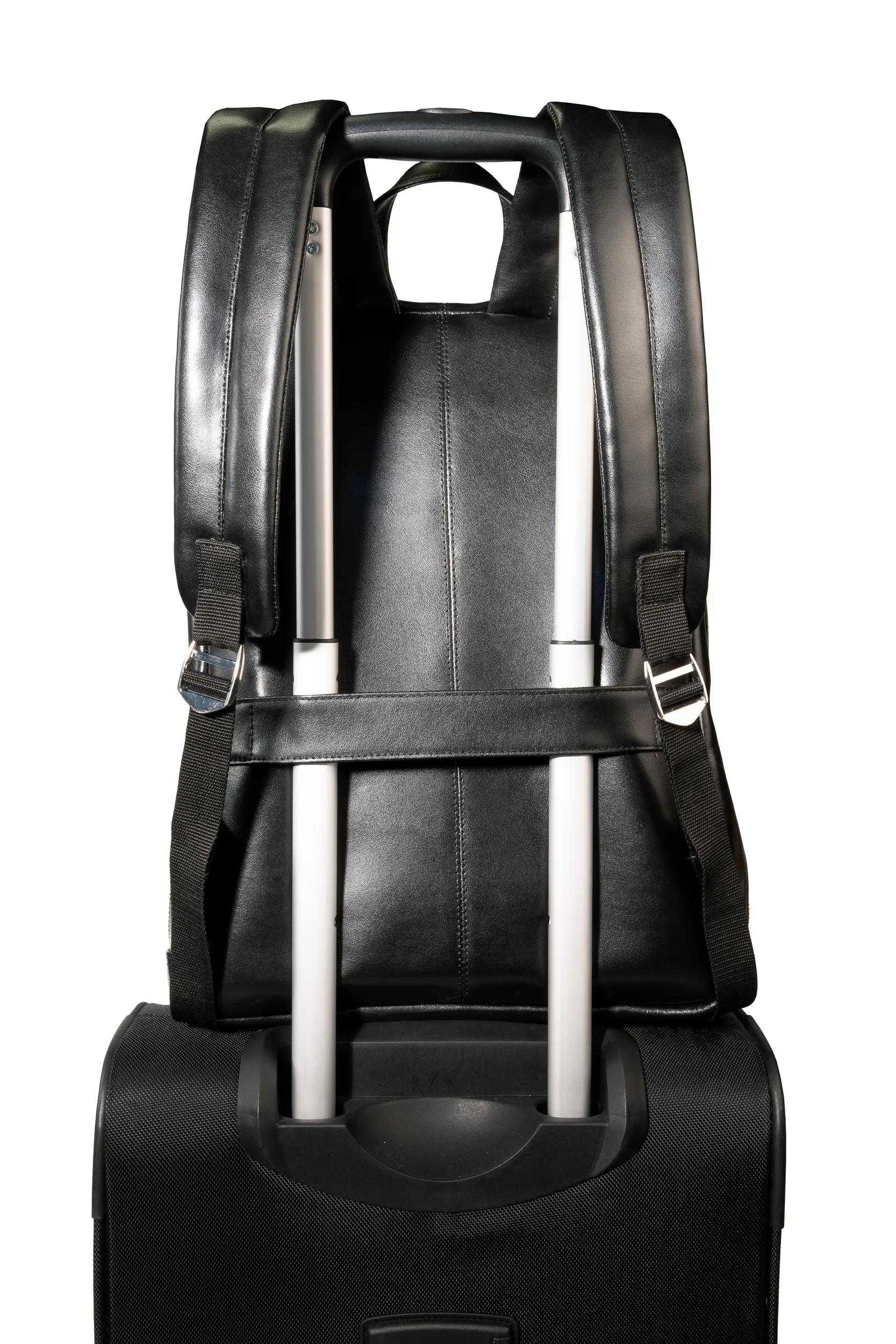 Mochila negra sobre maleta de ruedas negra con asas telescópicas plateadas.