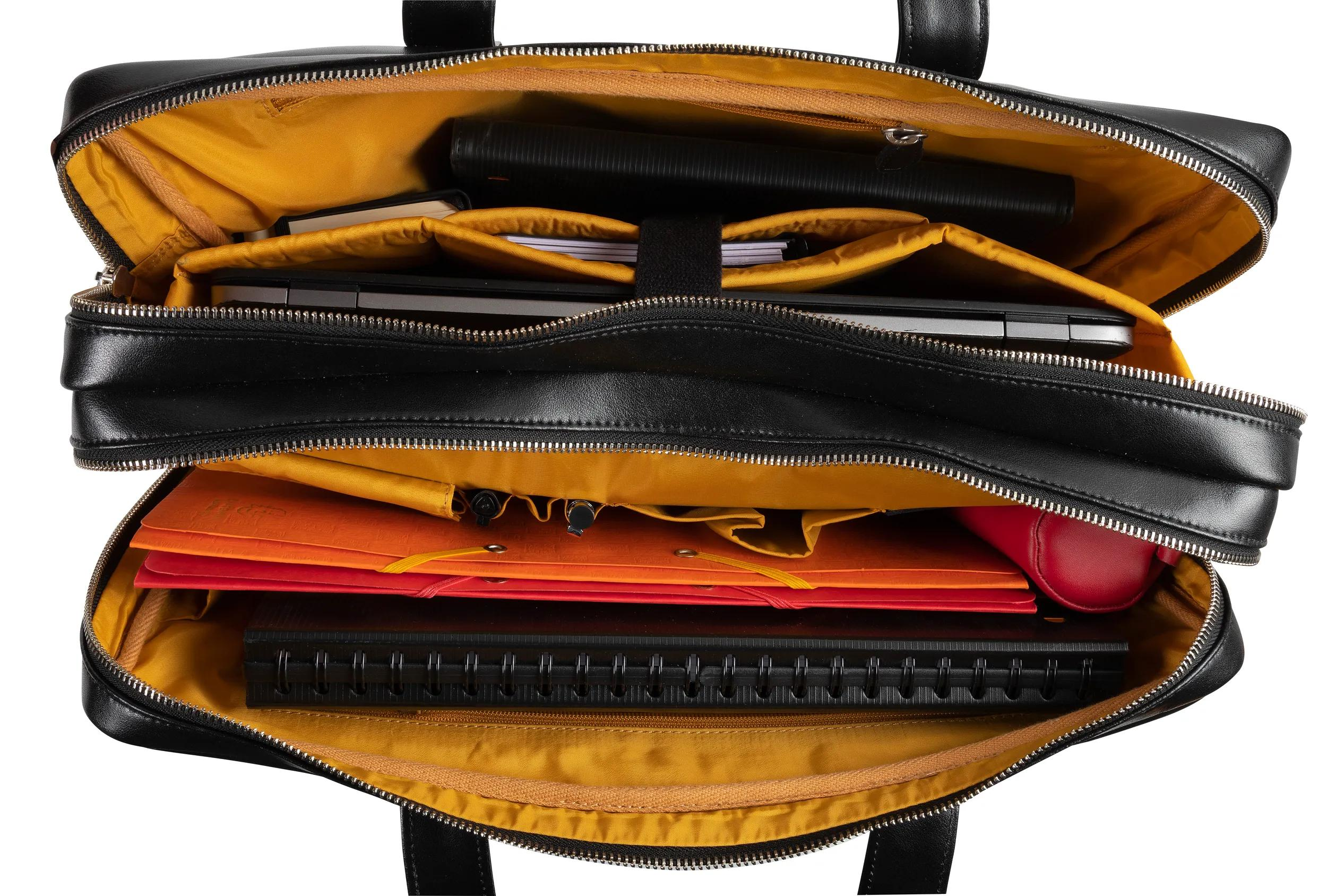 Bolso de cuero negro con forro amarillo, lleno de portátil, carpetas y cuadernos.