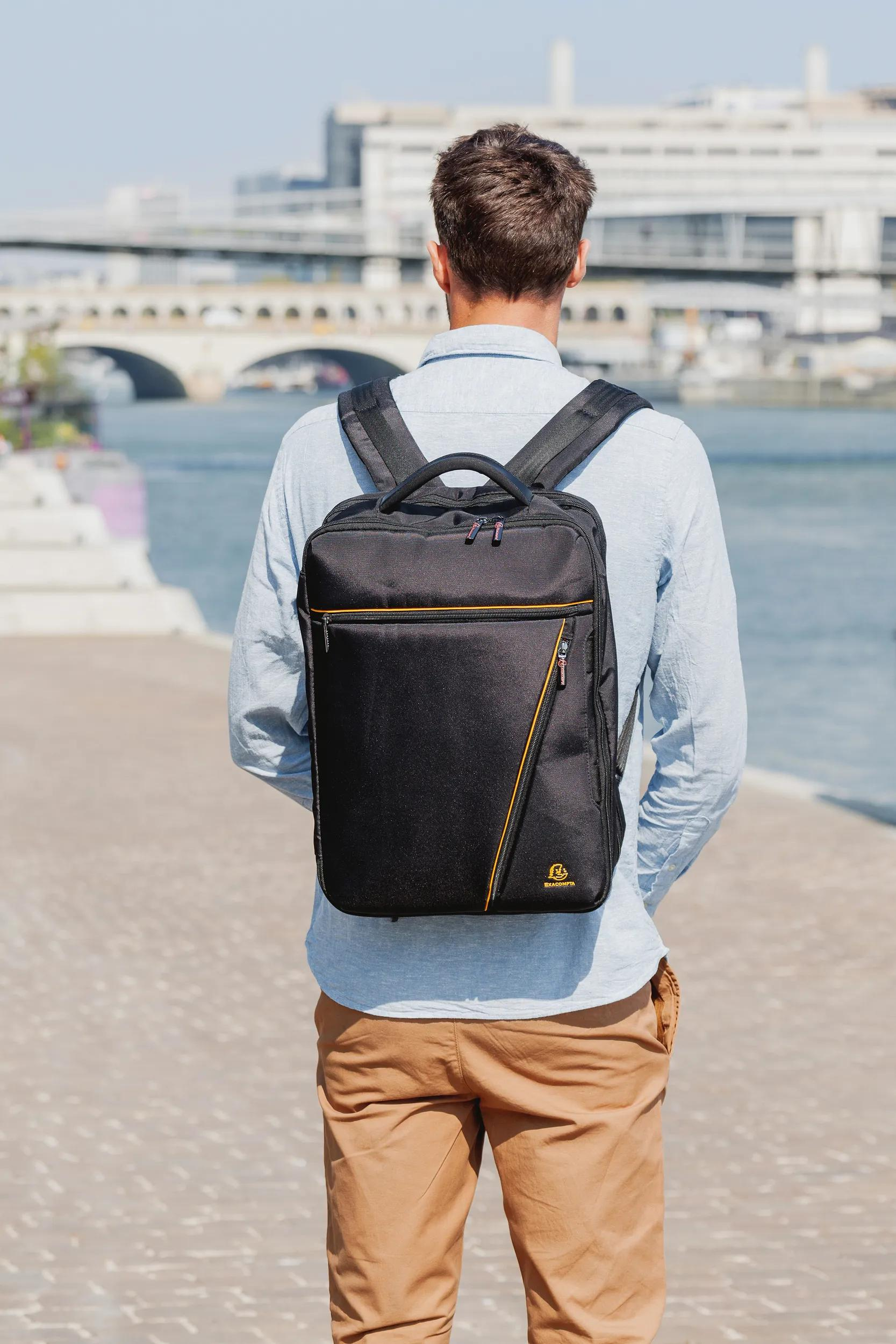 Hombre con mochila negra al aire libre junto al agua.