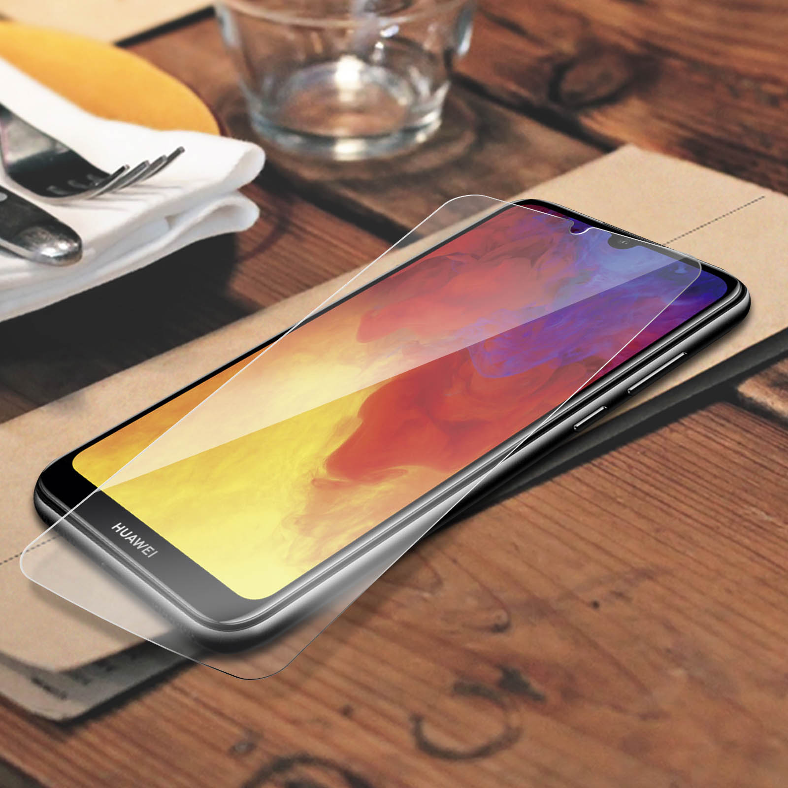Uno smartphone Huawei con pellicola protettiva su un tavolo di legno.