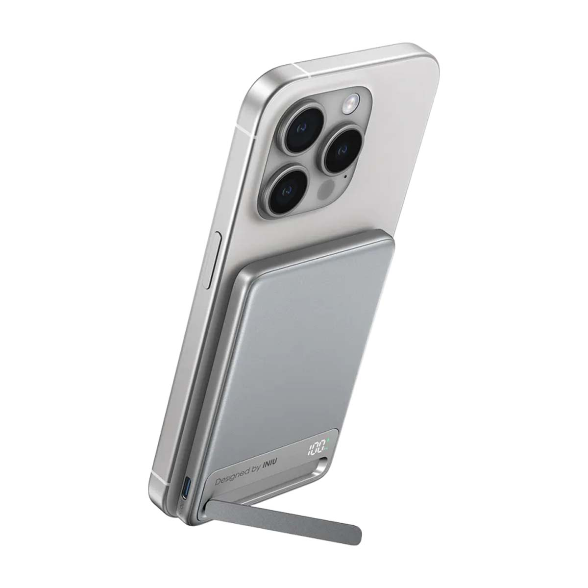 Un iPhone plateado con un cargador plateado adjunto que funciona como soporte.
