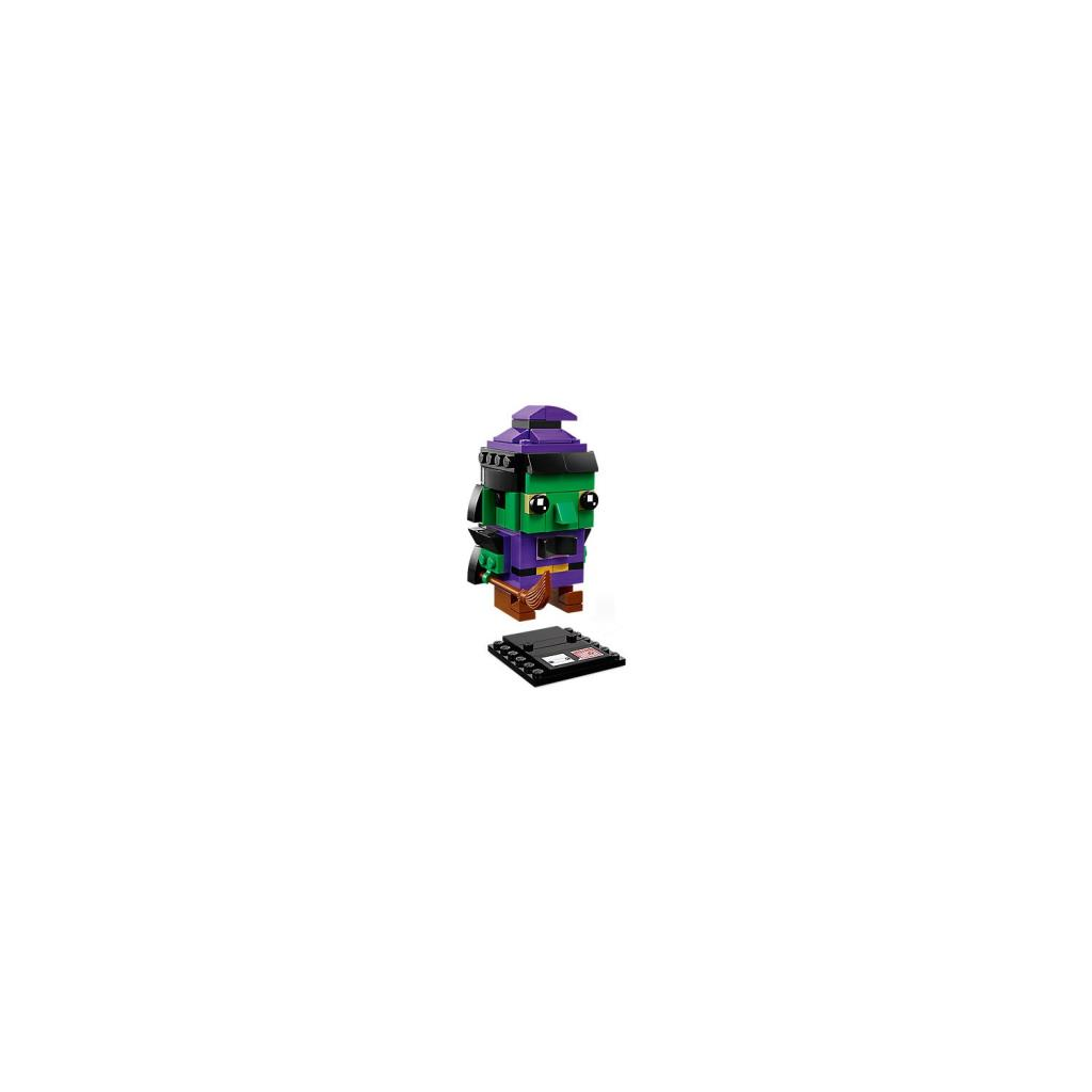 Ein grüner Lego-Hexen-Charakter mit lila Hut und Besen steht auf einer schwarzen Platte.